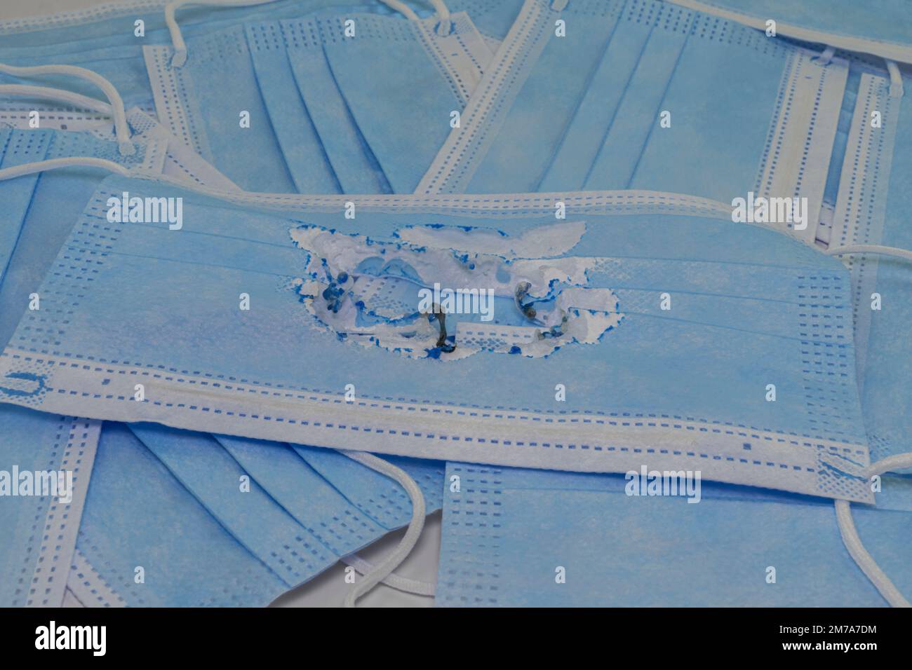 Utilisé (brûlé) masque médical bleu sur le fond de nouveaux masques (non utilisés). Le concept de la fin de la pandémie. Annuler le mode masque. Zéro covi Banque D'Images