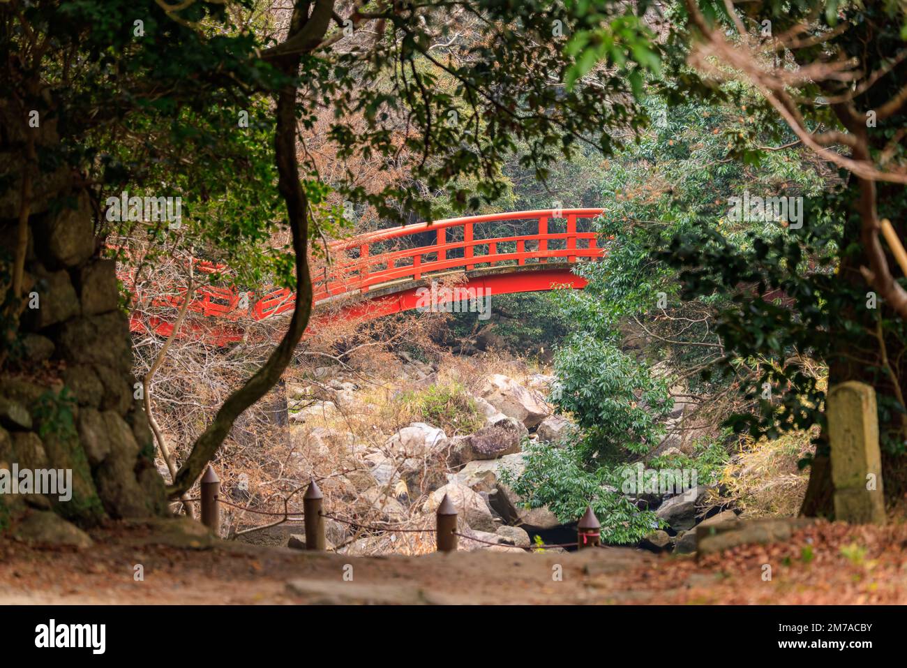 Le pont rouge traverse la crique rocheuse dans un paysage japonais boisé Banque D'Images