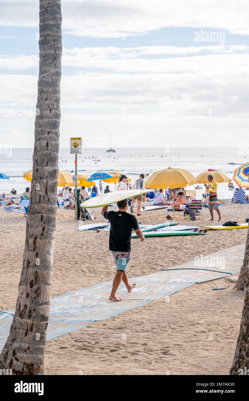 Honolulu, Hawaï - 29 décembre 2022 : homme transportant une planche de surf à Waikiki Beach. Banque D'Images