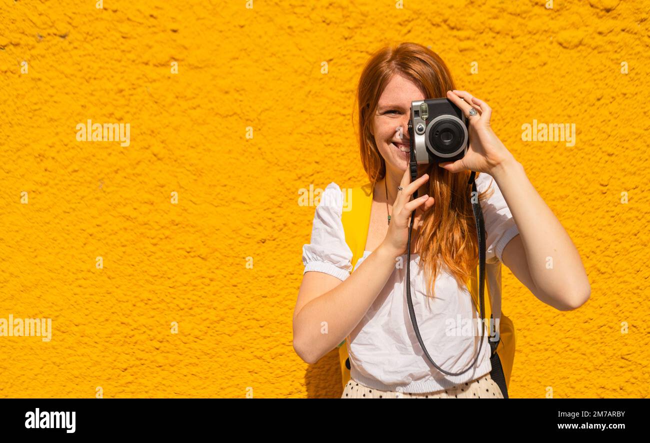 Femme faisant une photo de quelque chose sur fond jaune Banque D'Images