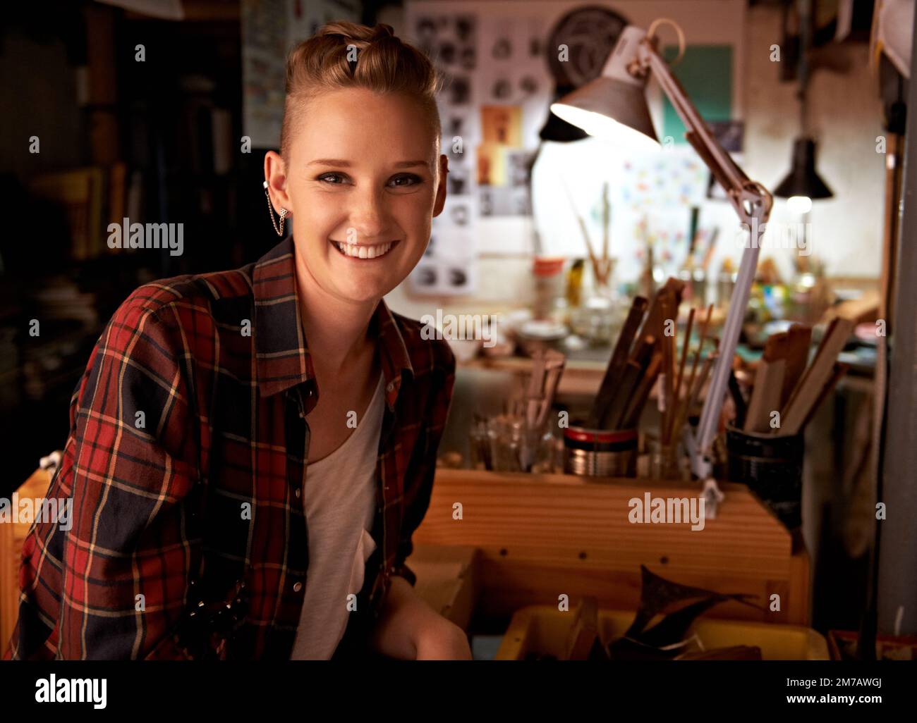 Heureux dans son propre espace de travail. une belle jeune femme assise dans un atelier. Banque D'Images