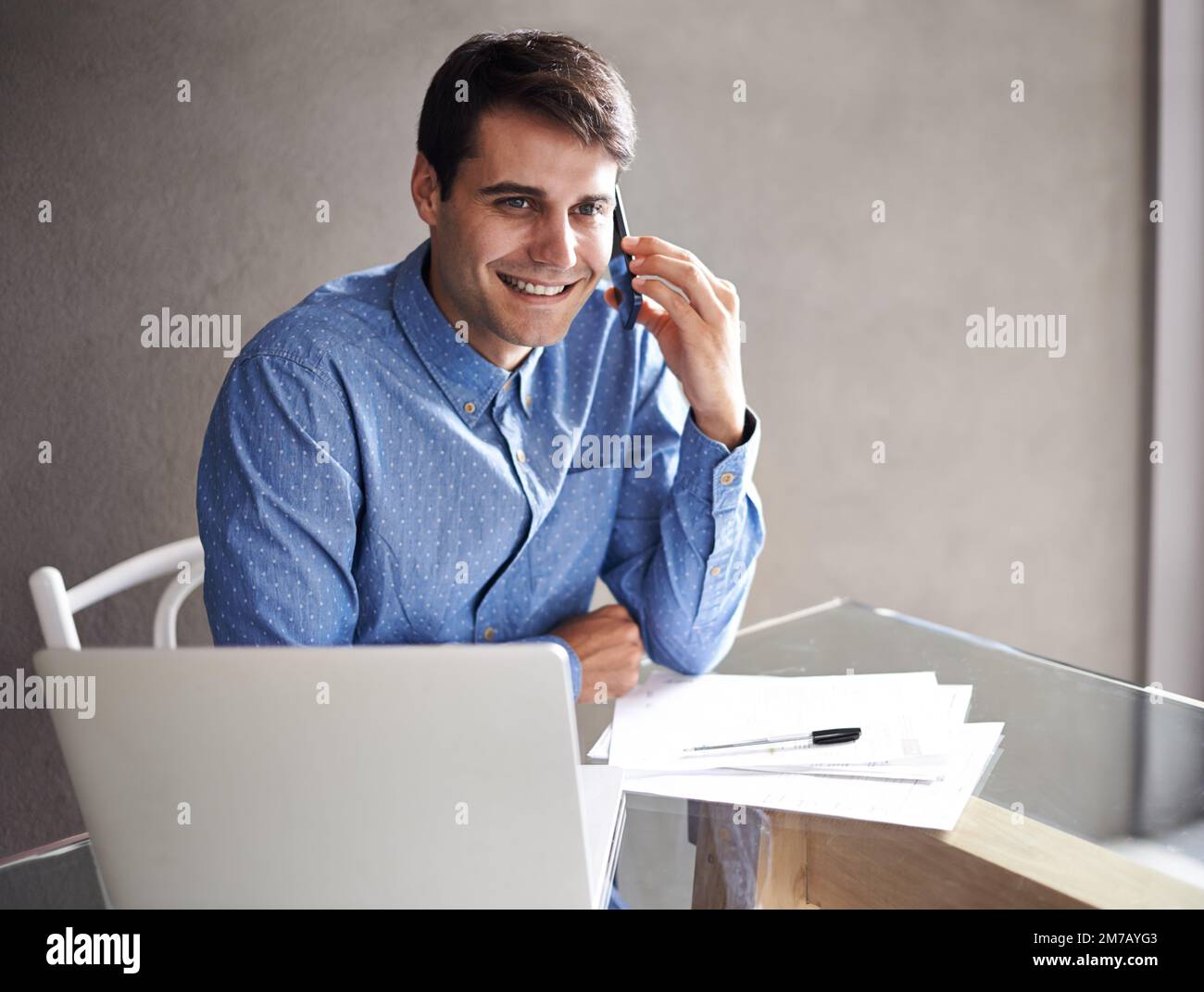 HES a réalisé un projet passionnant en cours de réalisation. Un jeune homme d'affaires confiant parlant au téléphone tout en étant assis à son bureau. Banque D'Images