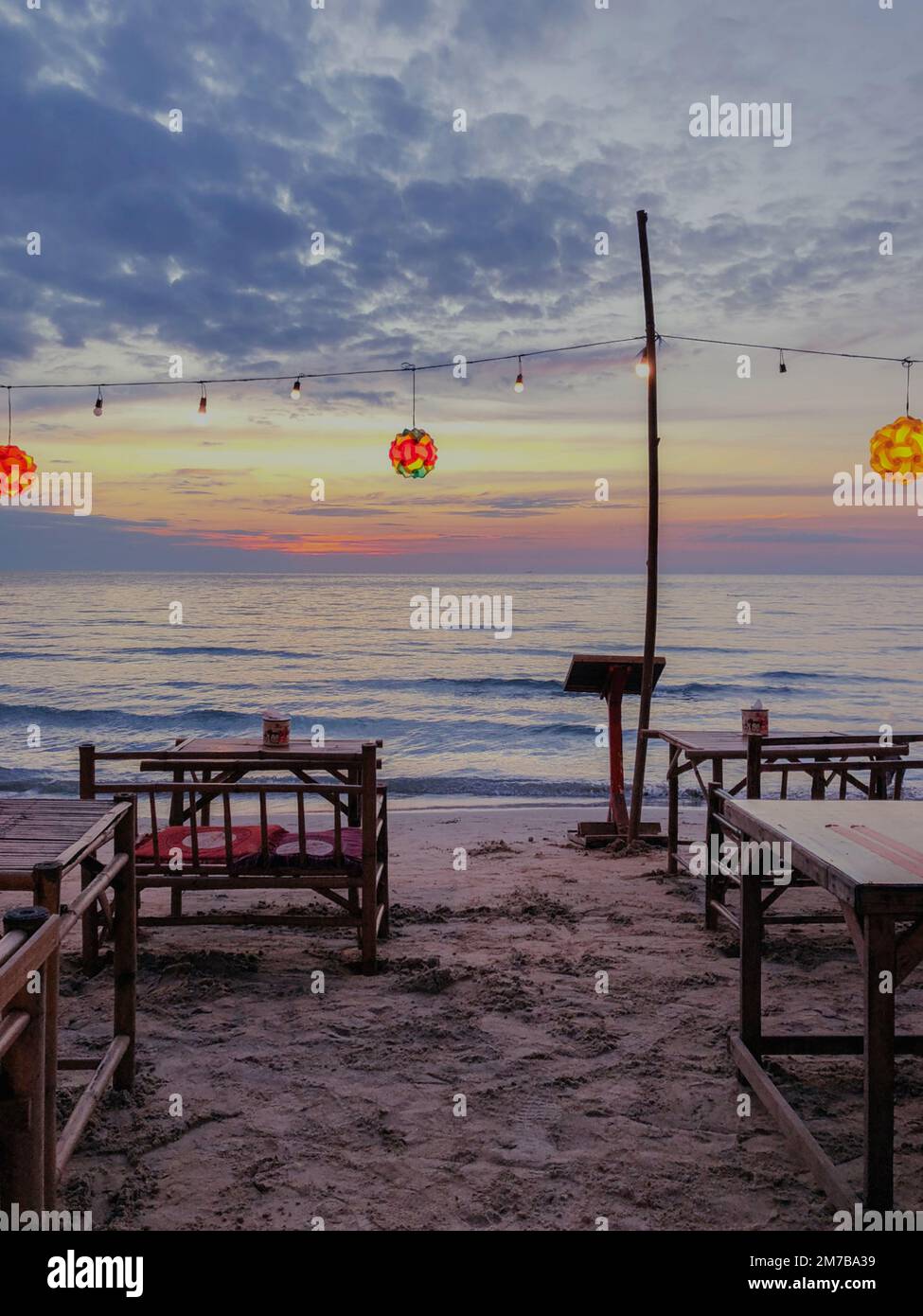 Vue verticale d'un restaurant sur la plage en Thaïlande avec des lanternes colorées au coucher du soleil Banque D'Images