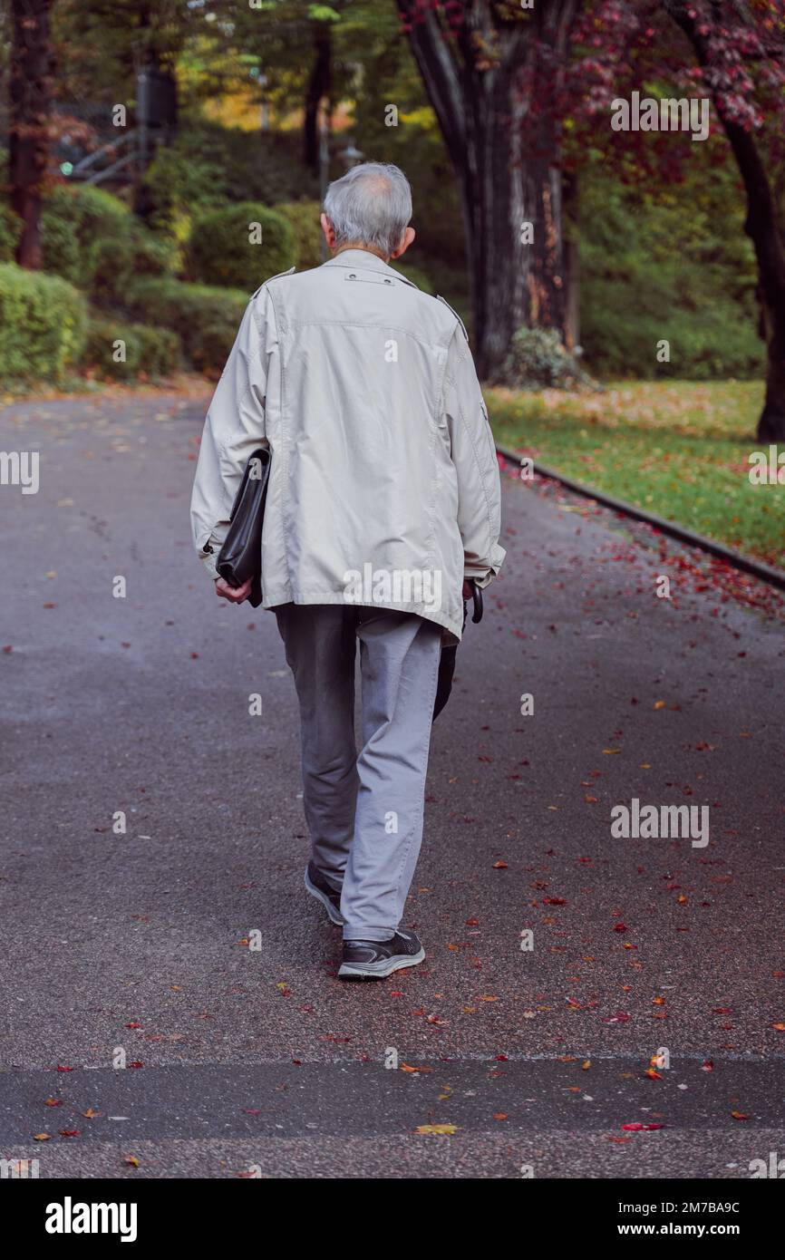 Photo verticale d'un homme adulte vu de l'arrière, marchant dans un parc Banque D'Images