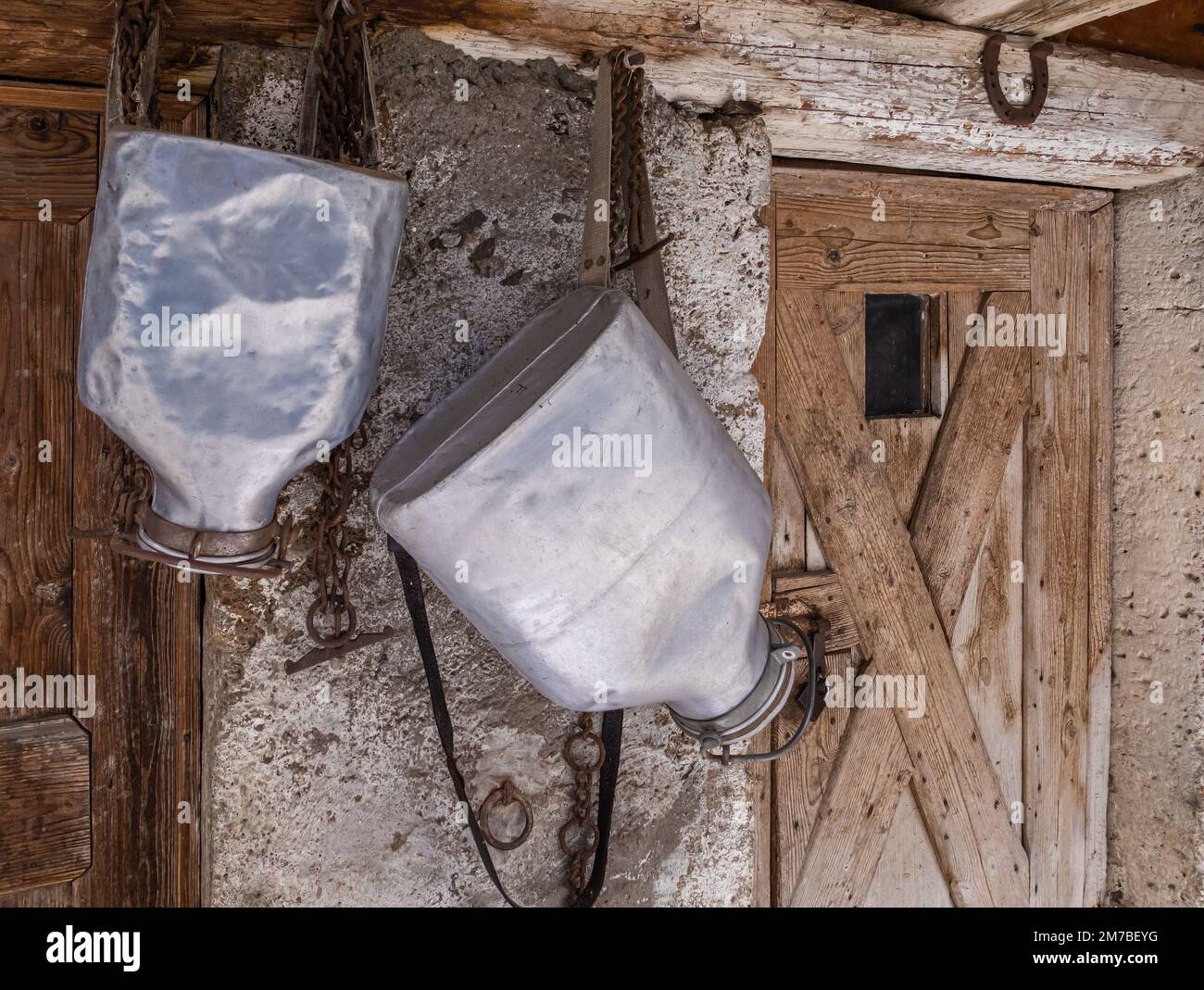 Sacs à dos en aluminium pour le transport du lait après la traite, accrochés devant la grange. Banque D'Images