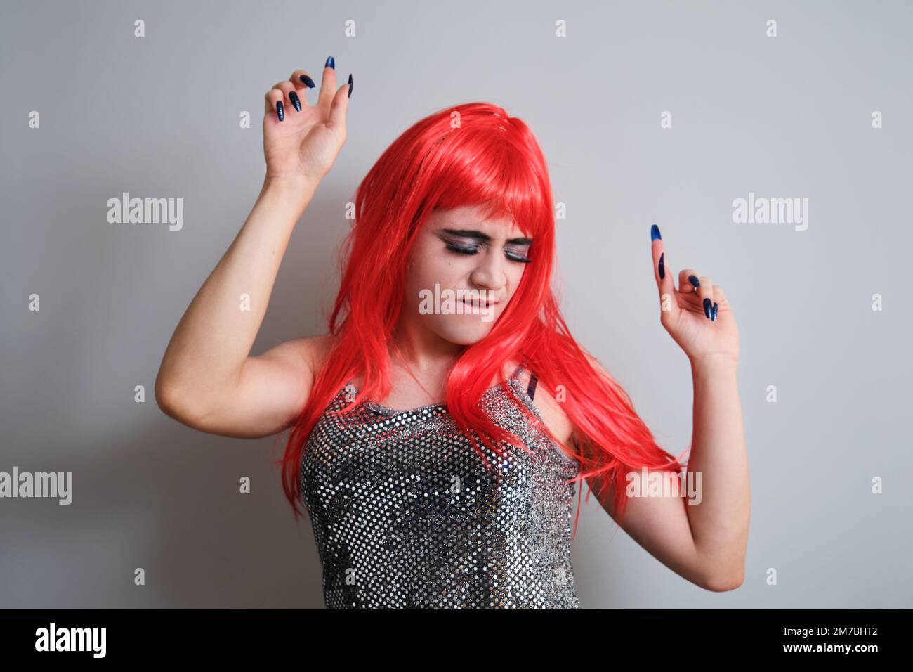Portrait d'une reine de drag portant une perruque rouge et dansant. Banque D'Images