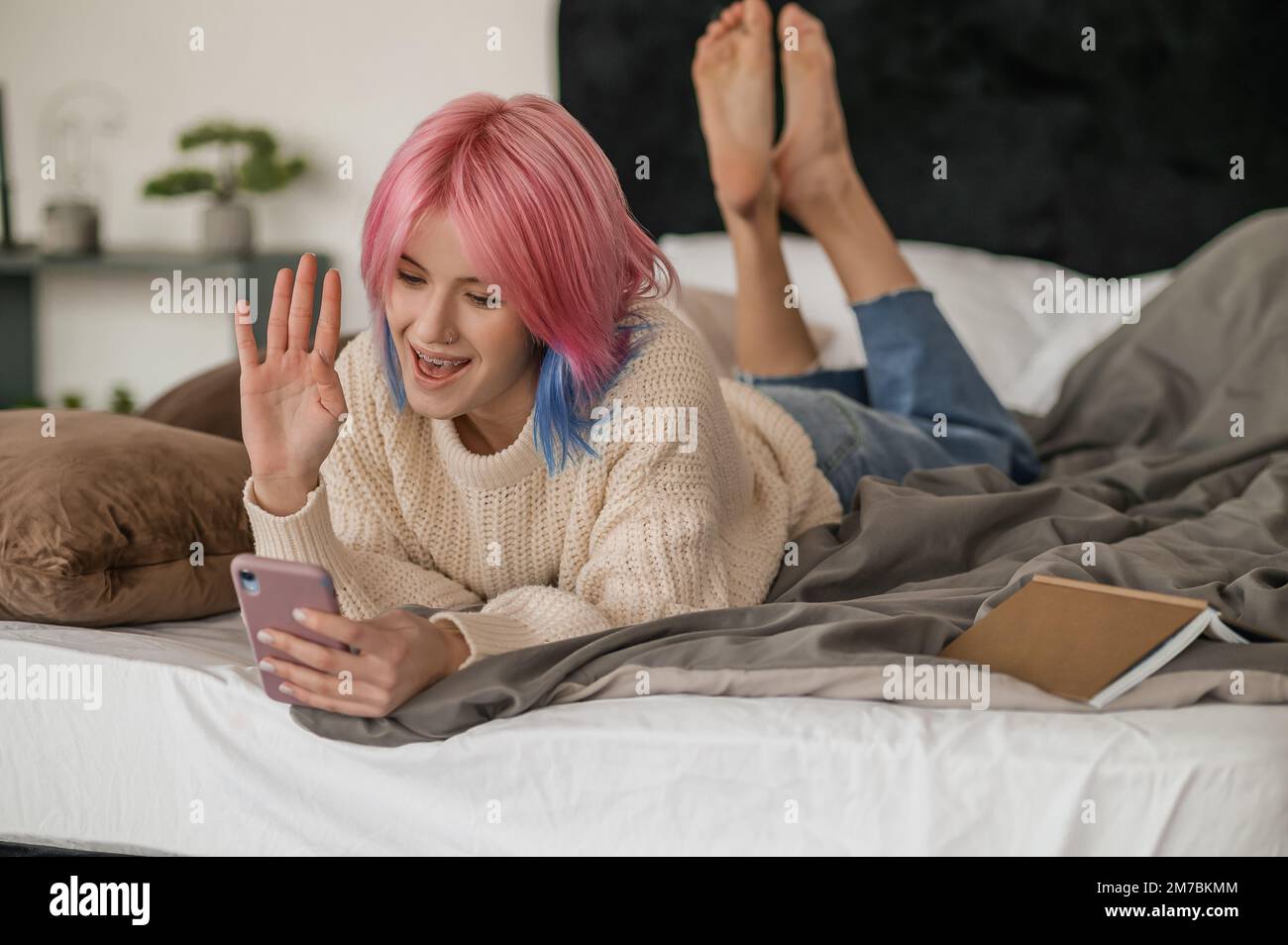 Une jeune fille joyeuse aux cheveux roses qui communique sur le téléphone intelligent Banque D'Images