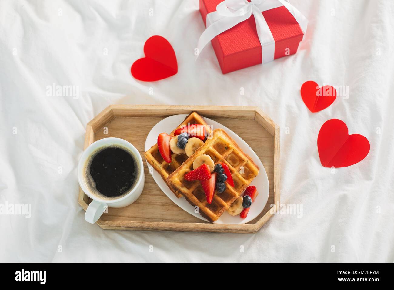 Le petit-déjeuner de la Saint-Valentin comprend du café et des gaufres belges sur le linge de lit blanc. Vue de dessus Banque D'Images