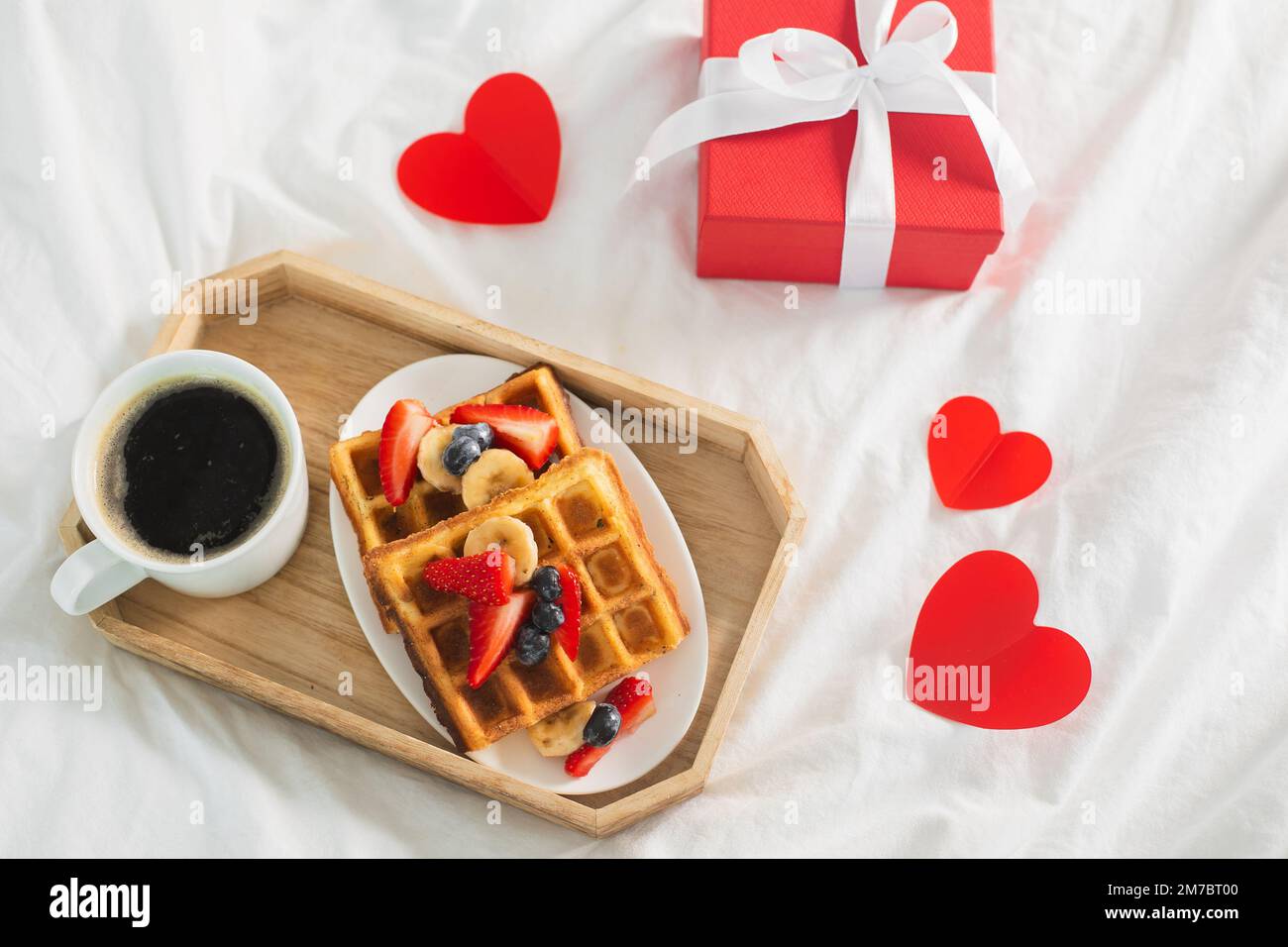 Le petit-déjeuner de la Saint-Valentin comprend du café et des gaufres belges sur le linge de lit blanc. Vue de dessus Banque D'Images