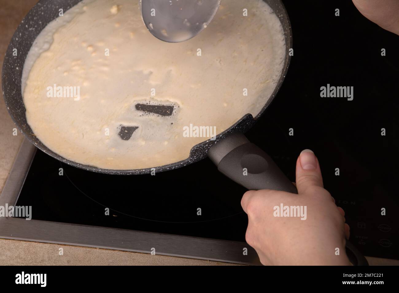 pâte à crêpes photo sur une casserole chaude, mains dans le cadre Banque D'Images