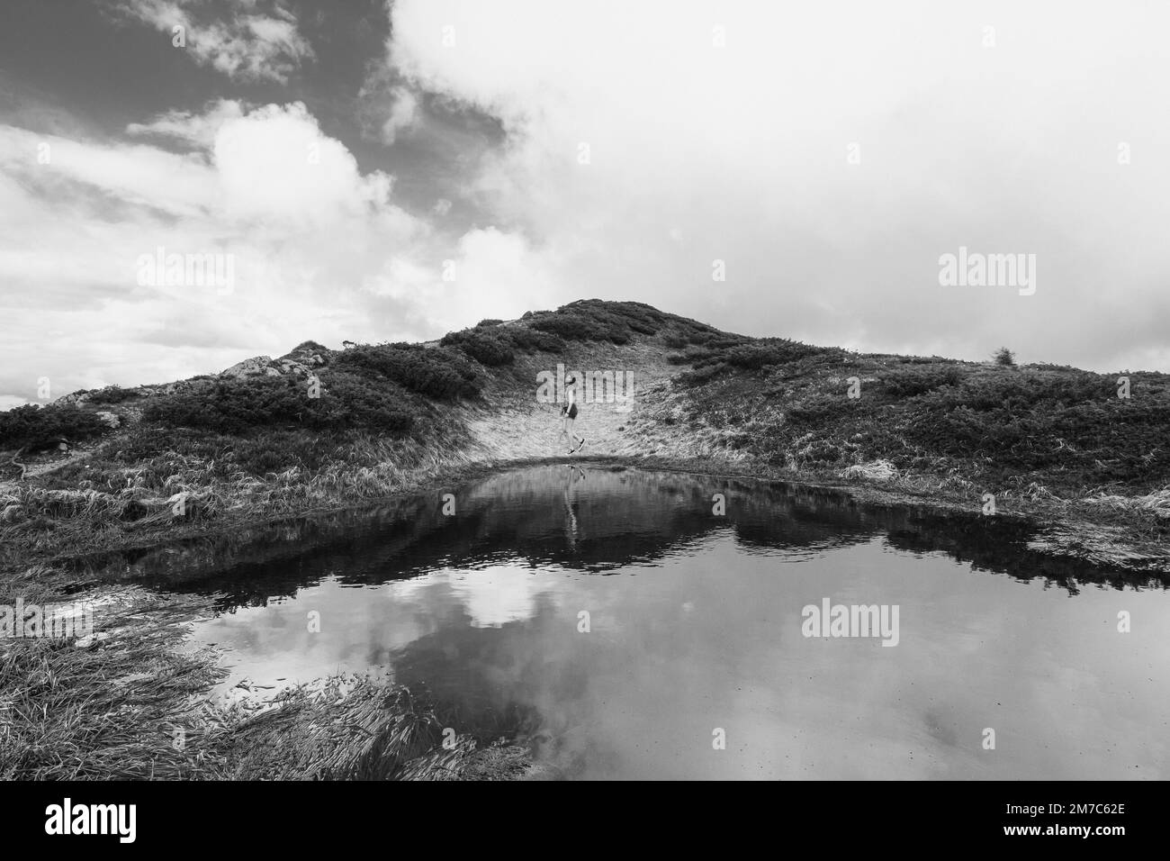 Randonneur sur une rive vallonnée d'une rivière photo monochrome paysage Banque D'Images