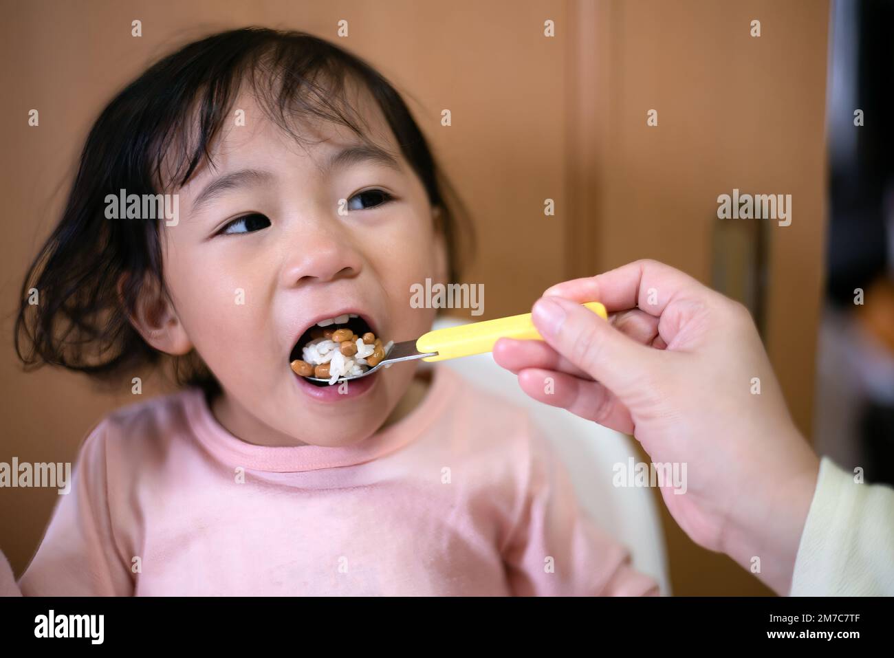 Un tout-petit mangeant natto - un haricot de soja japonais fermenté. Une alimentation saine. Alimentation manuelle Banque D'Images