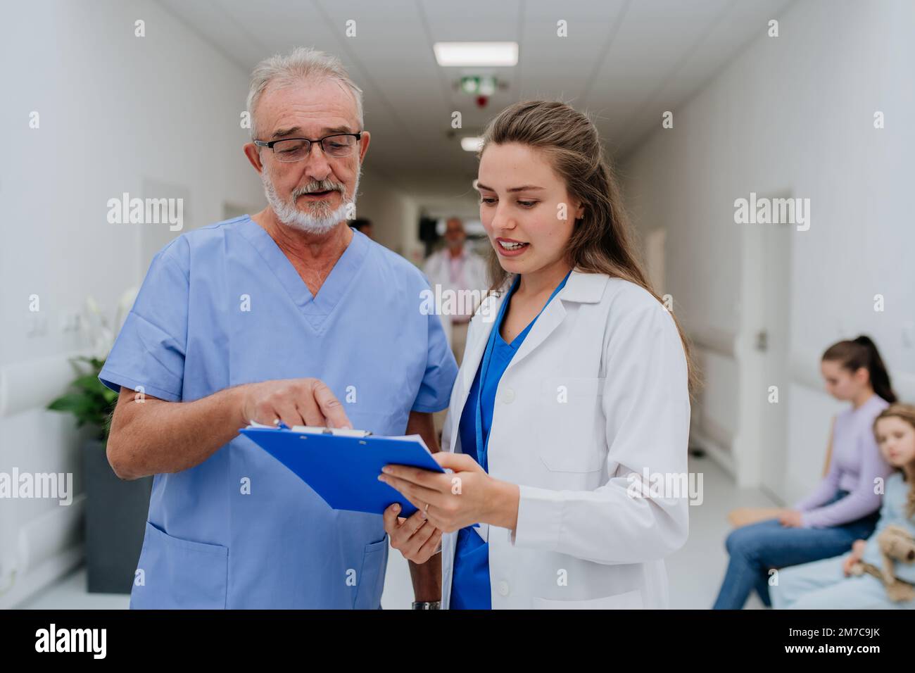 Un médecin plus âgé donne des conseils à son jeune collègue, discutant dans le couloir de l'hôpital. Concept de soins de santé. Banque D'Images