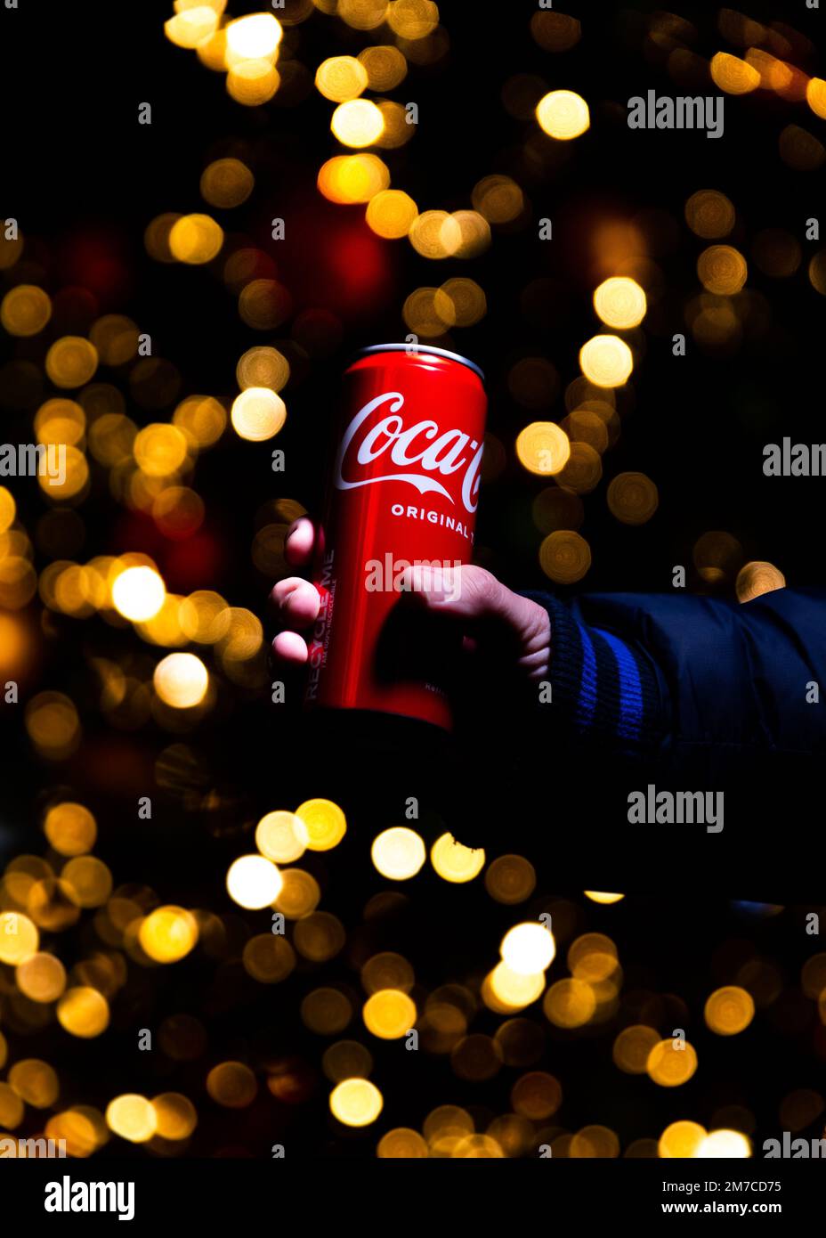 Belgrade, Serbie - 5 janvier 2023: Coca Cola peut à la main avec des lumières de Noël et la décoration en arrière-plan tourné la nuit dans la ville de Belgrade, Serbie Banque D'Images