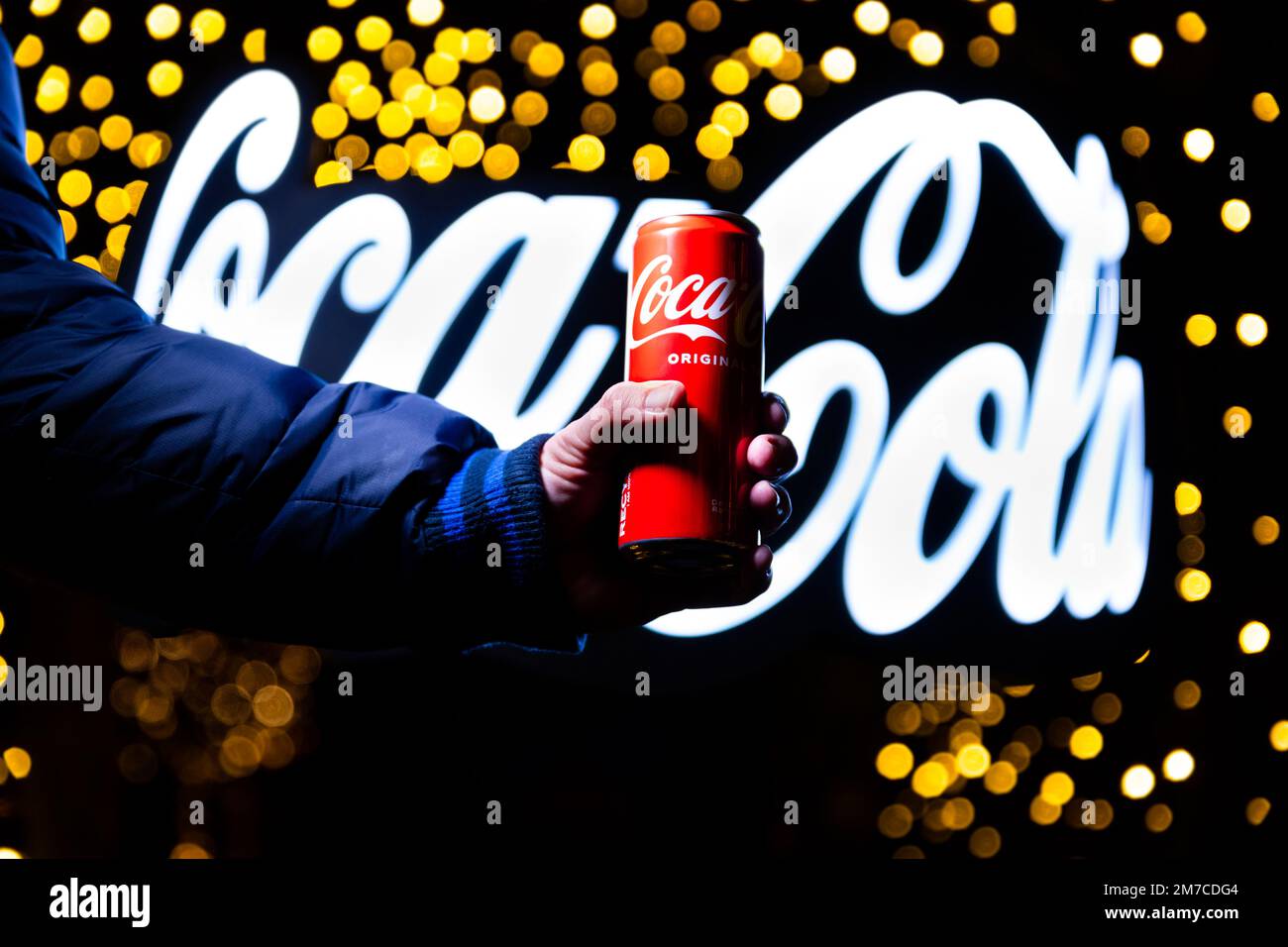 Belgrade, Serbie - 5 janvier 2023: Coca Cola peut à la main avec le signe Coca Cola dans l'arrière-plan tourné la nuit dans la ville de Belgrade, Serbie Banque D'Images