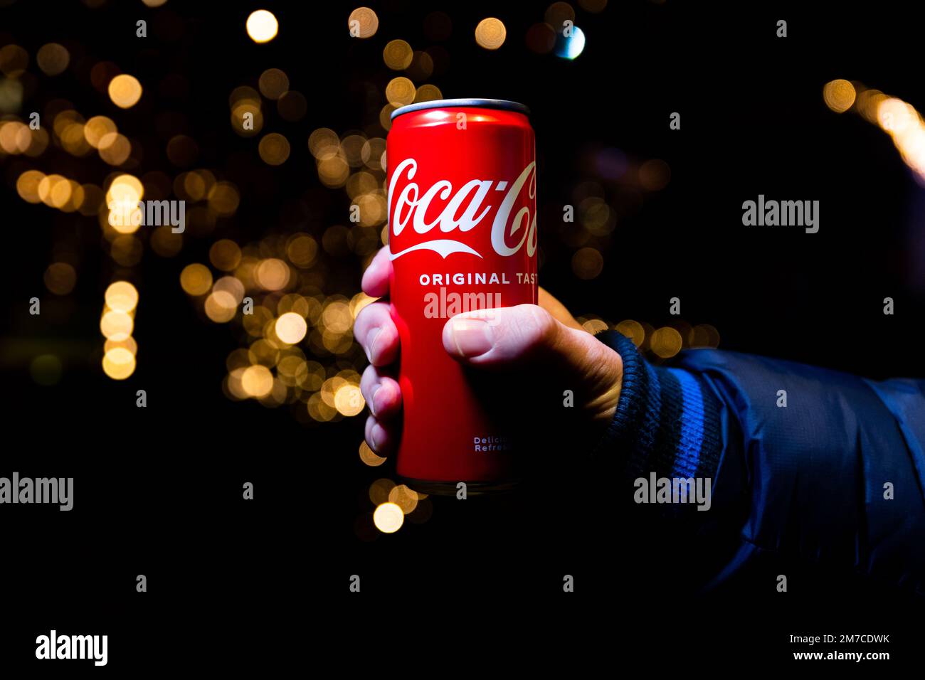 Belgrade, Serbie - 5 janvier 2023: Coca Cola peut à la main avec des lumières de Noël et la décoration en arrière-plan tourné la nuit dans la ville de Belgrade, Serbie Banque D'Images