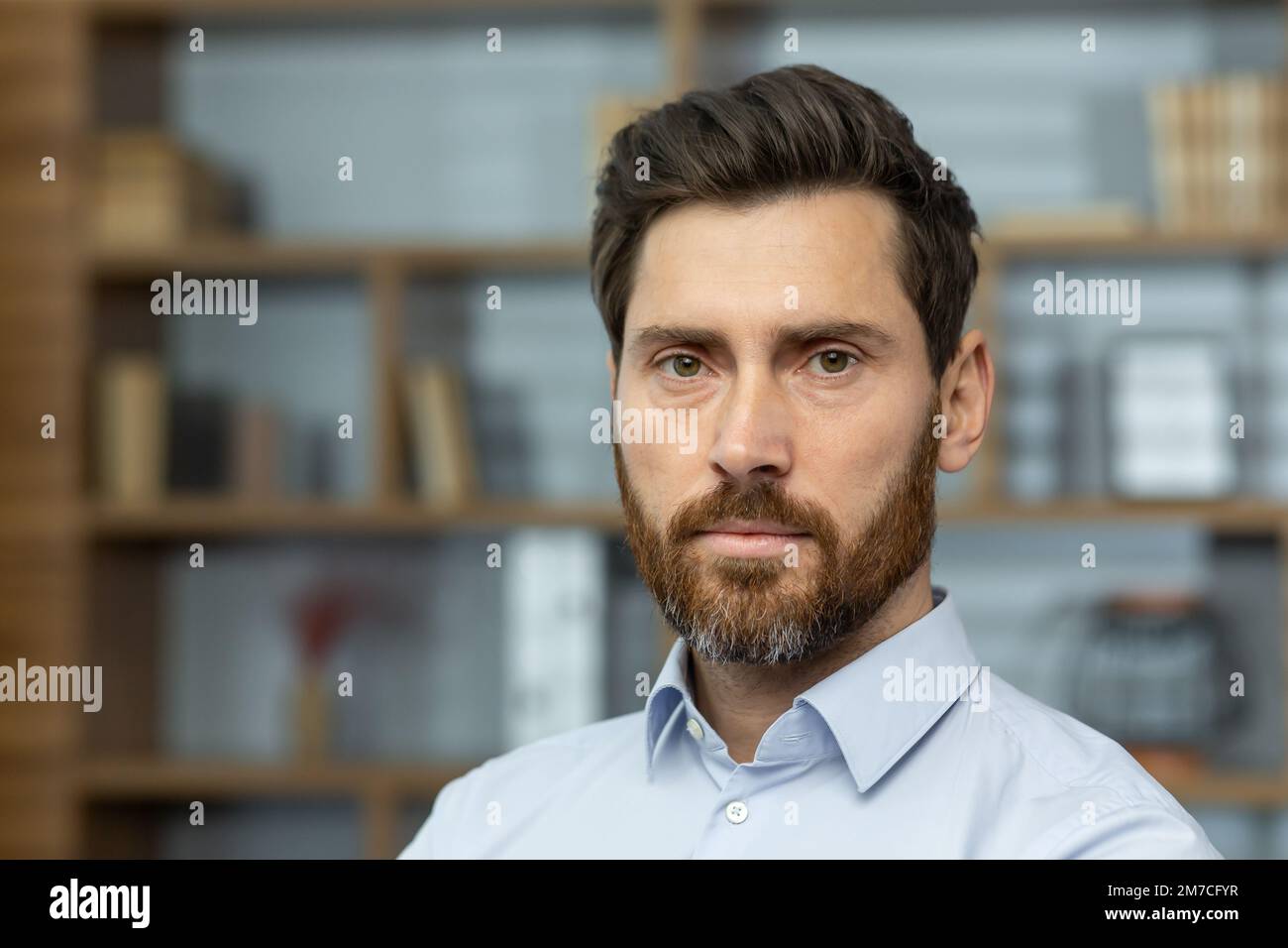 Gros plan photo d'un patron sérieux en chemise dans un bureau à domicile, homme mûr avec barbe regardant la pensée de la caméra, homme d'affaires tête d'impression investisseur. Banque D'Images