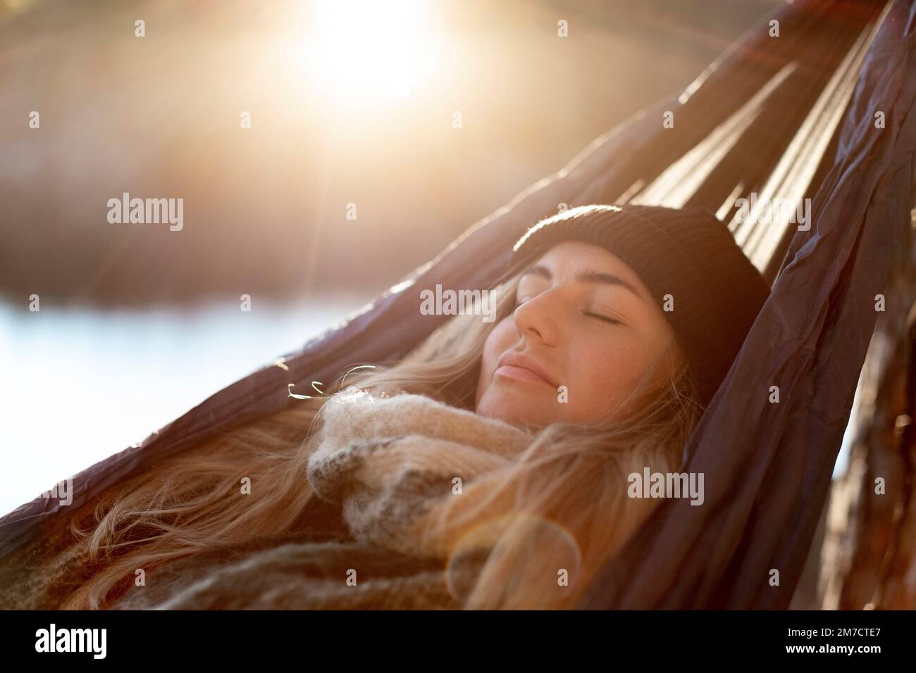 Jeune femme avec les yeux fermés se détendant sur le hamac pendant la journée ensoleillée Banque D'Images