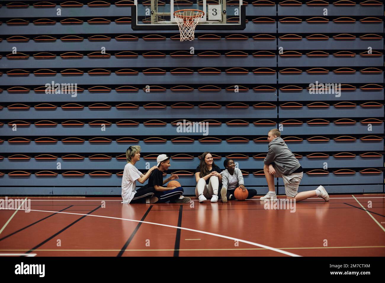 Des garçons et des filles souriants qui parlent les uns avec les autres au terrain de basket-ball de l'école Banque D'Images
