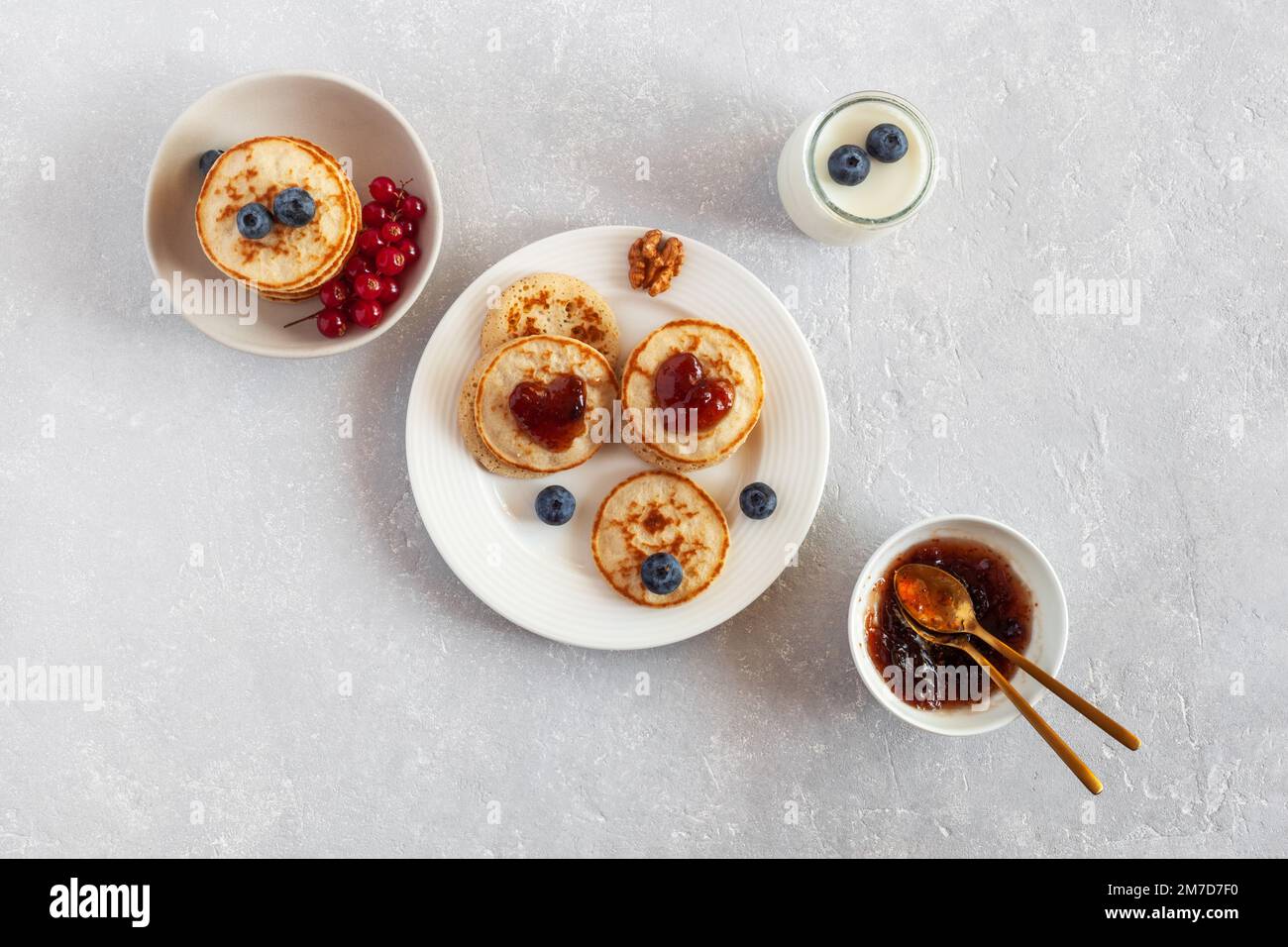 Yaourt et mini crêpes décorées de confiture en forme de coeur et de baies fraîches, idée du petit déjeuner de la Saint-Valentin, vue du dessus Banque D'Images