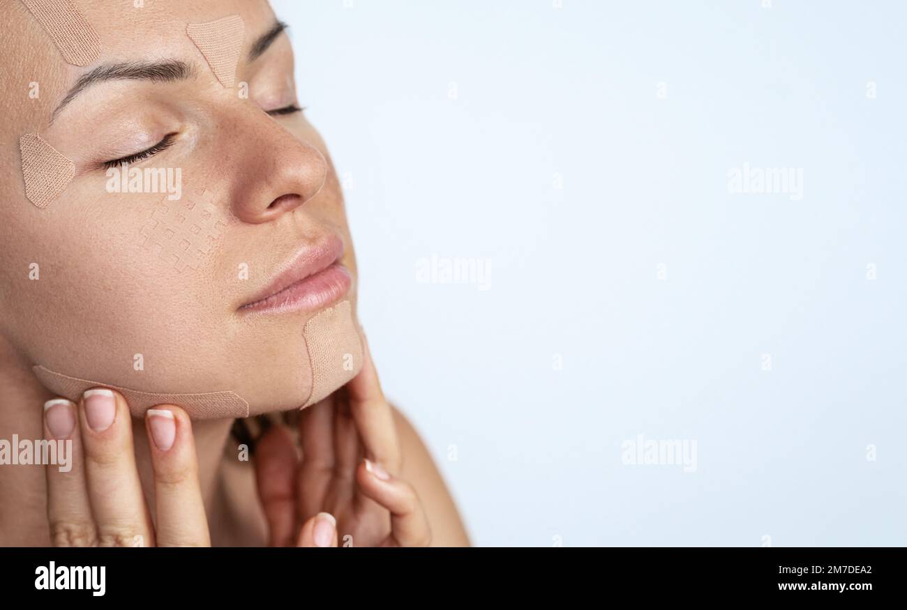 Ruban de kinésiologie faciale sur le visage femelle gros plan ruban de soin de peau beauté. Banque D'Images