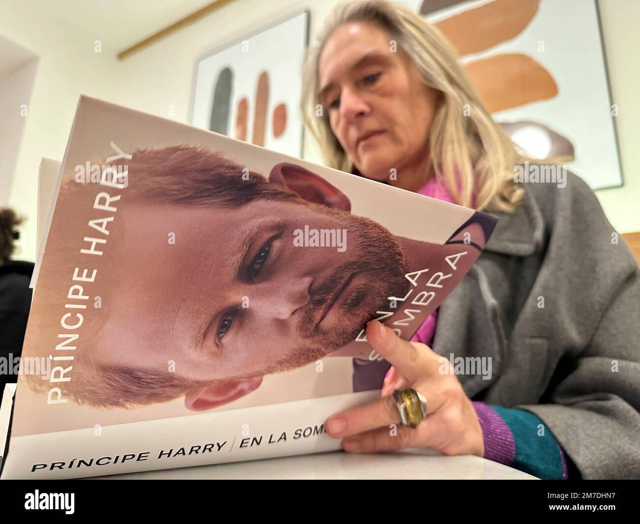A woman poses for a photo as she opens a copy of "En La Sombra" (In the