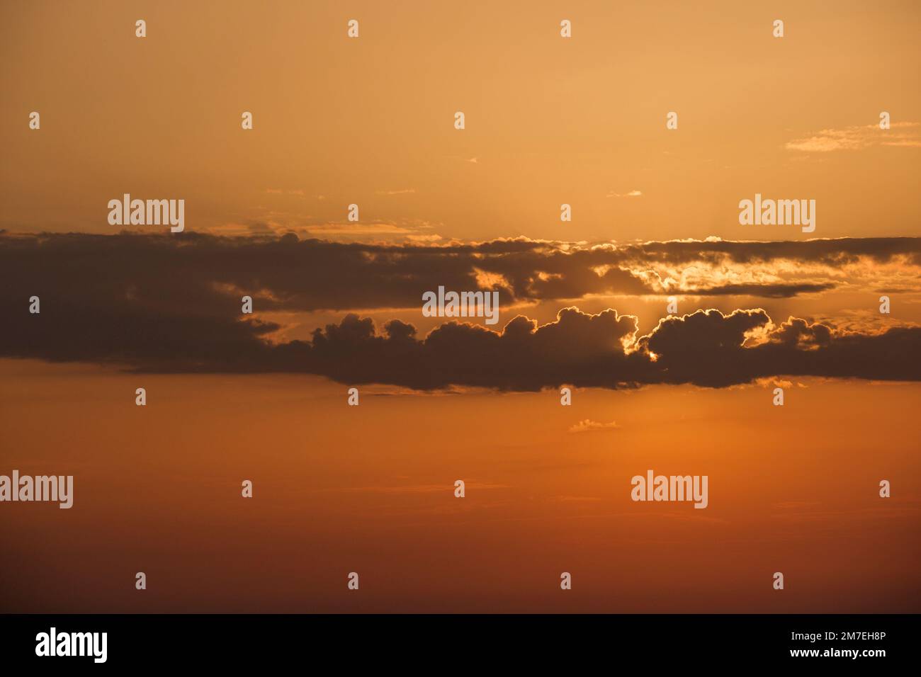 Des nuages et des conditions météorologiques spectaculaires à l'horizon au-dessus de la mer avec des reflets de la lumière du soleil sur la mer et des nuages roses profonds et colorés se reflétant dans l'eau de mer. Banque D'Images