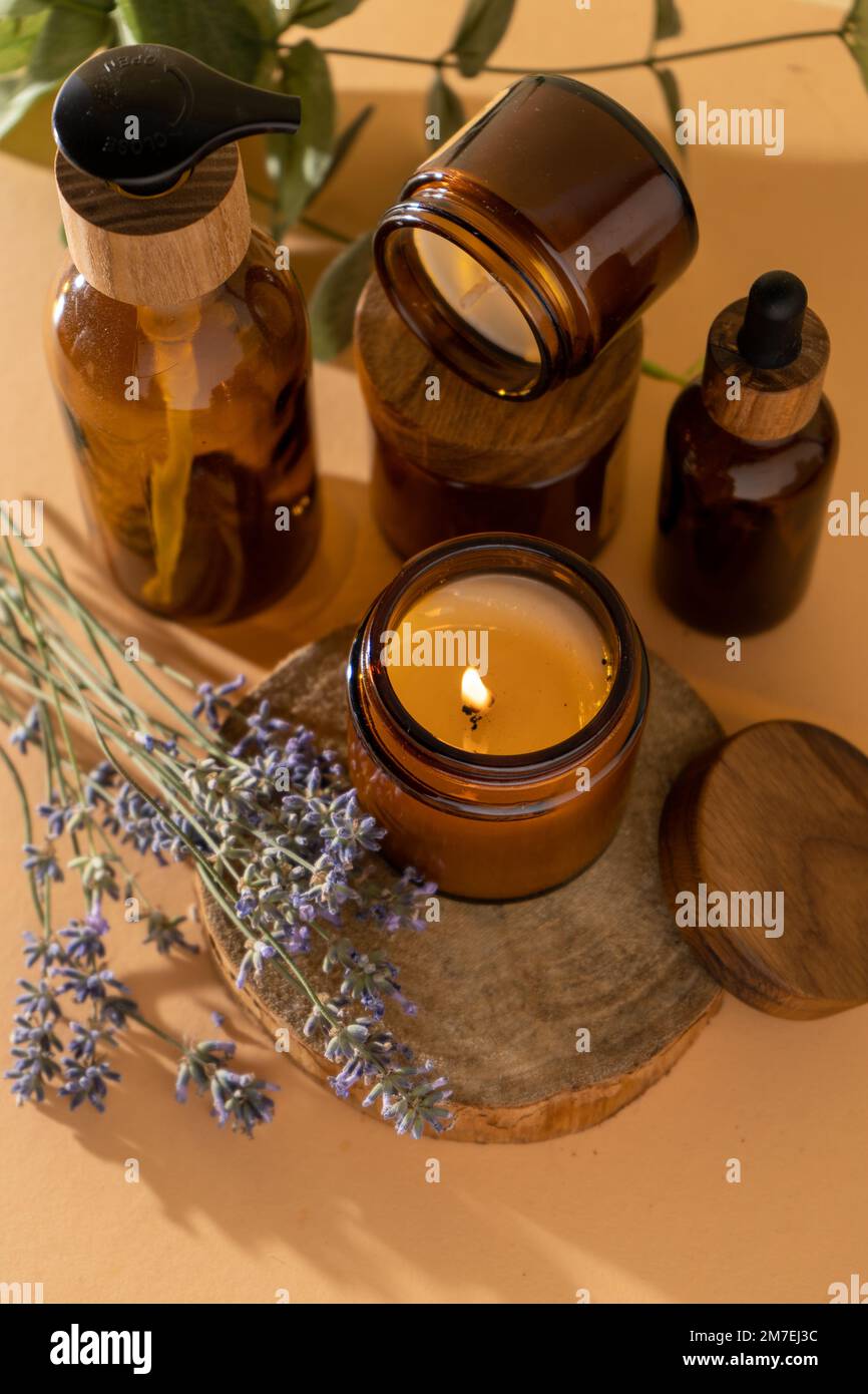 Bougies de soja dans un pot en verre. Aromathérapie. Bougie brûlante et lavande. Couvercle en bois pour bocaux. Arrière-plan beige. Confort et détente. Fait à la main. Décoration d'intérieur. Banque D'Images