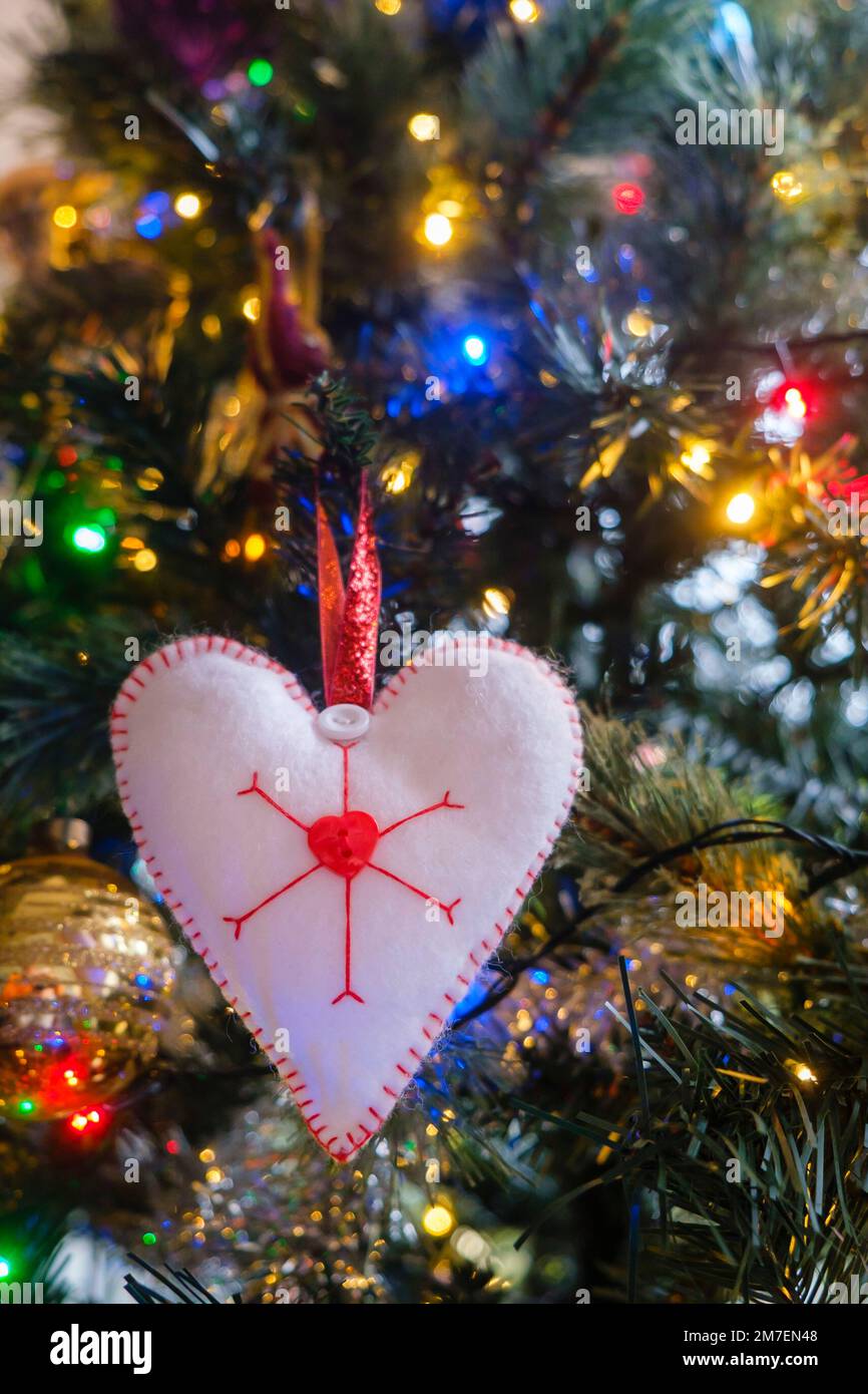 Une décoration en forme de coeur faite maison avec des flocons de neige accrochés à un arbre de noël. Banque D'Images