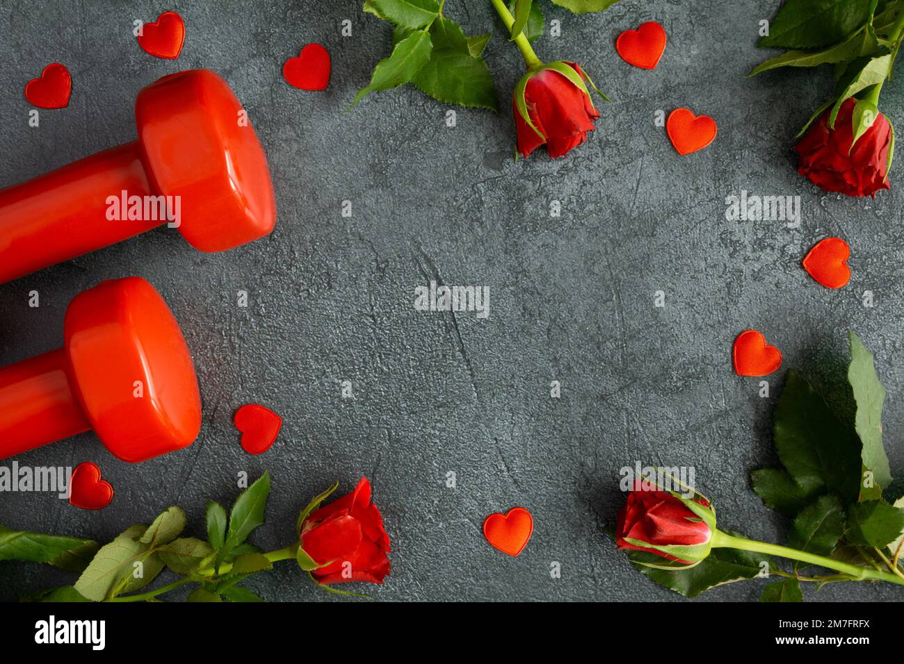 Haltères et roses rouges comme cadeau d'amour pour la Saint-Valentin, anniversaire, mariage. Gym, entraînement fitness plat avec espace de copie. Banque D'Images