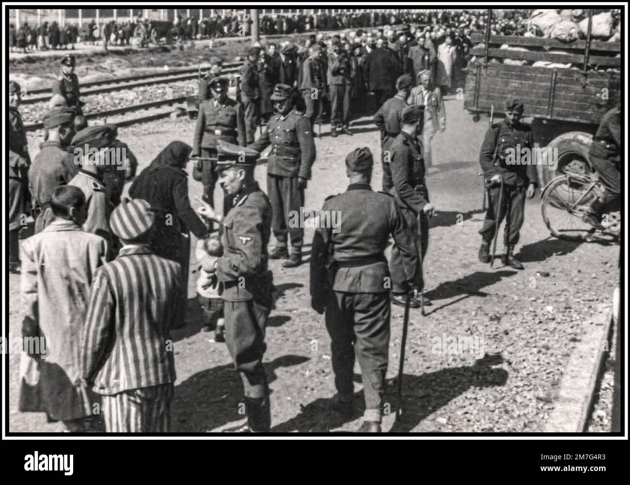 AUSCHWITZ-BIRKENAU LIGNE DE CLASSEMENT DE LA FILE D'ATTENTE ARRIVÉE- Une vision de l'enfer sur terre. 1944, les nazis «classent» (vie ou mort) les prisonniers sans méfiance sur le hall ferroviaire devant l'entrée du camp d'extermination d'Auschwitz-Birkenau. Le tristement célèbre camp d'Auschwitz a été créé sur ordre d'Adolf Hitler dans les années 1940, pendant l'occupation de la Pologne par l'Allemagne nazie pendant la guerre mondiale 2, puis permis par Heinrich Luitpold Himmler, le Reichsführer du Schutzstaffel, et membre dirigeant du Parti nazi d'Allemagne Banque D'Images