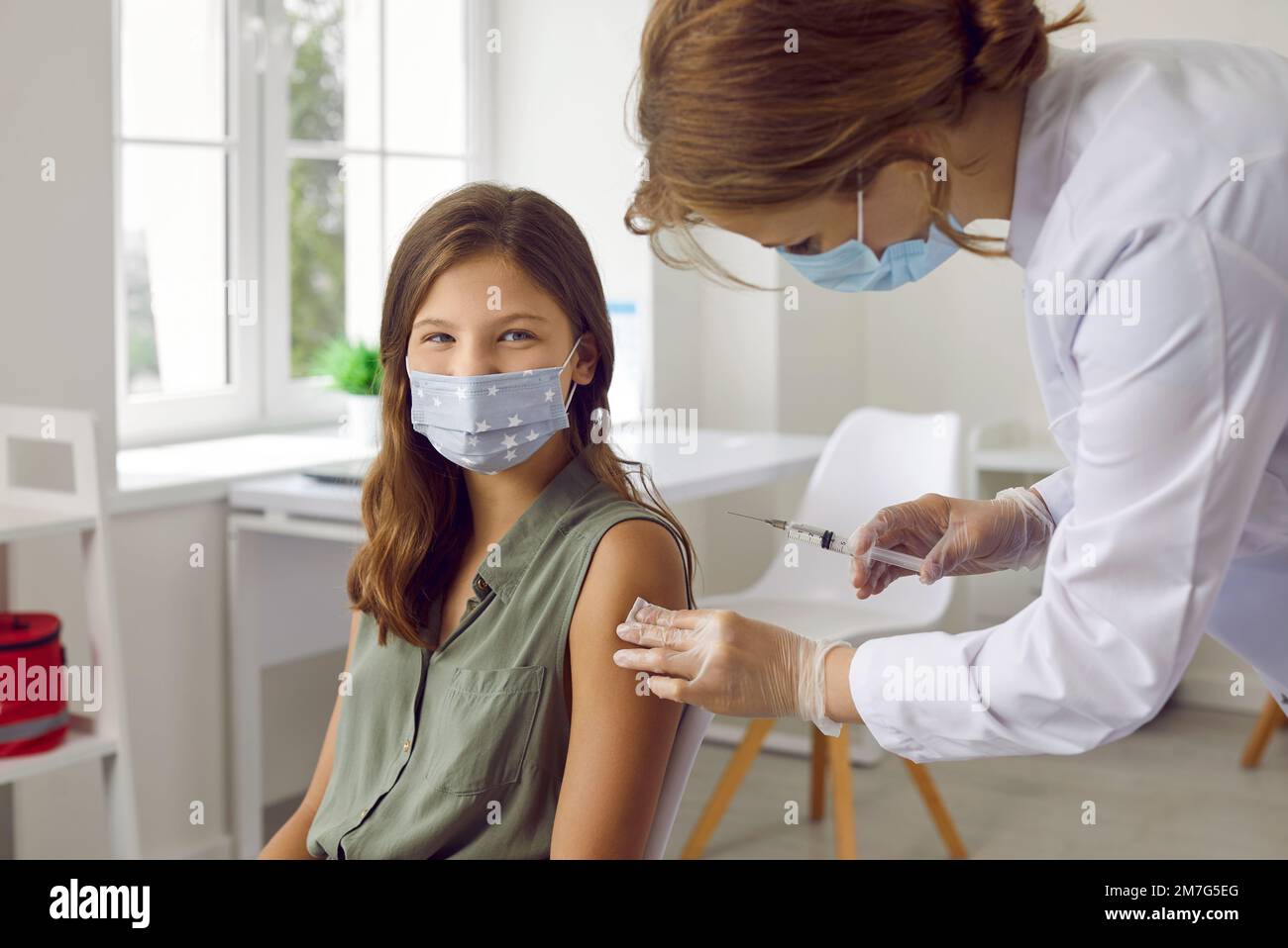 Enfant souriant sous masque recevant un vaccin contre une infection à Covid au centre de vaccination. Banque D'Images