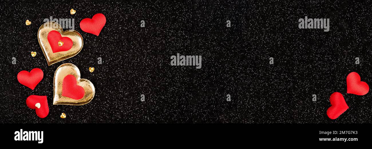 Longue banderole horizontale pour la Saint-Valentin avec espace de copie. Composition avec de nombreux coeurs rouges et dorés sur fond noir scintillant Banque D'Images