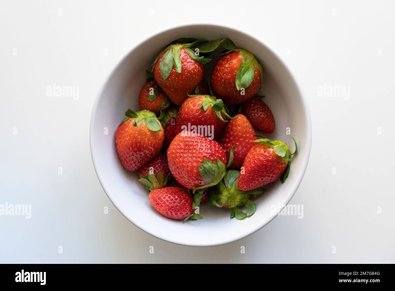 Vue de dessus des fraises fraîches dans un bol blanc isolé sur fond blanc Banque D'Images