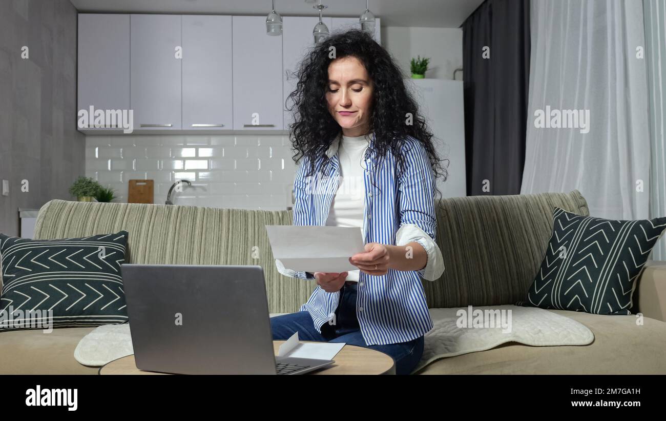 Une femme vérifie les factures de services publics et saisit les informations dans un ordinateur portable Banque D'Images