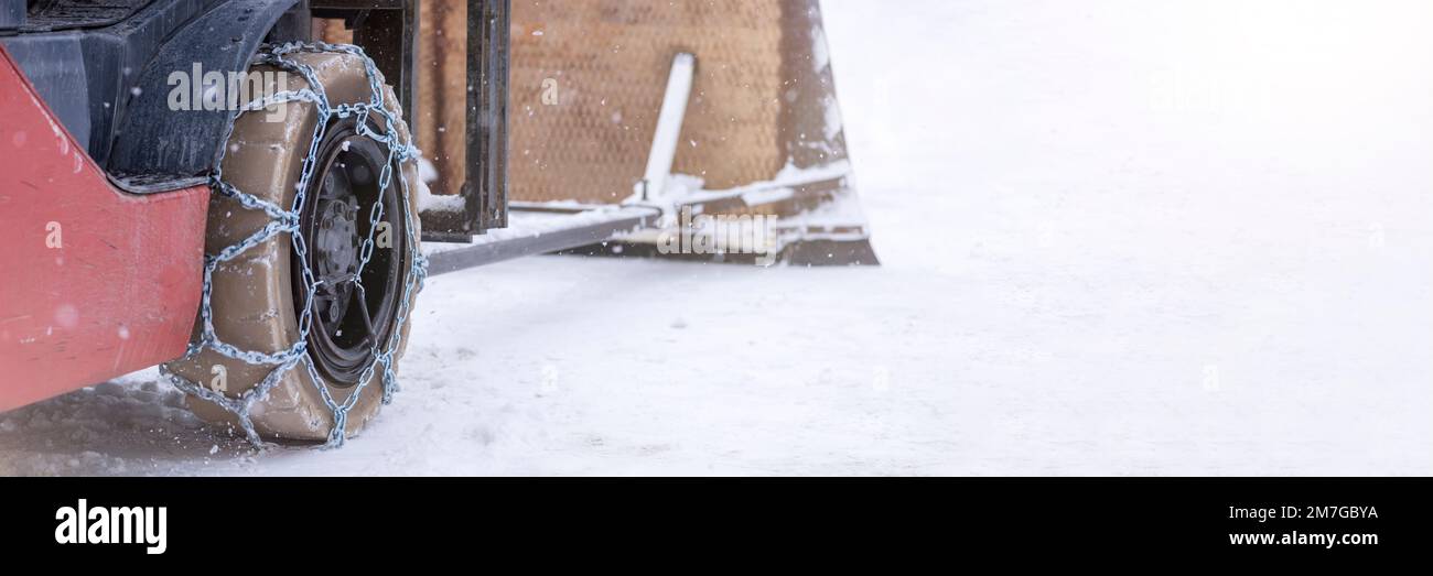 Roue du tracteur avec chaîne. Tracteur ou chargeur sur une route enneigée glissante. Les chargeurs se conduisent sur la neige avec des chaînes antidérapantes. Banque D'Images