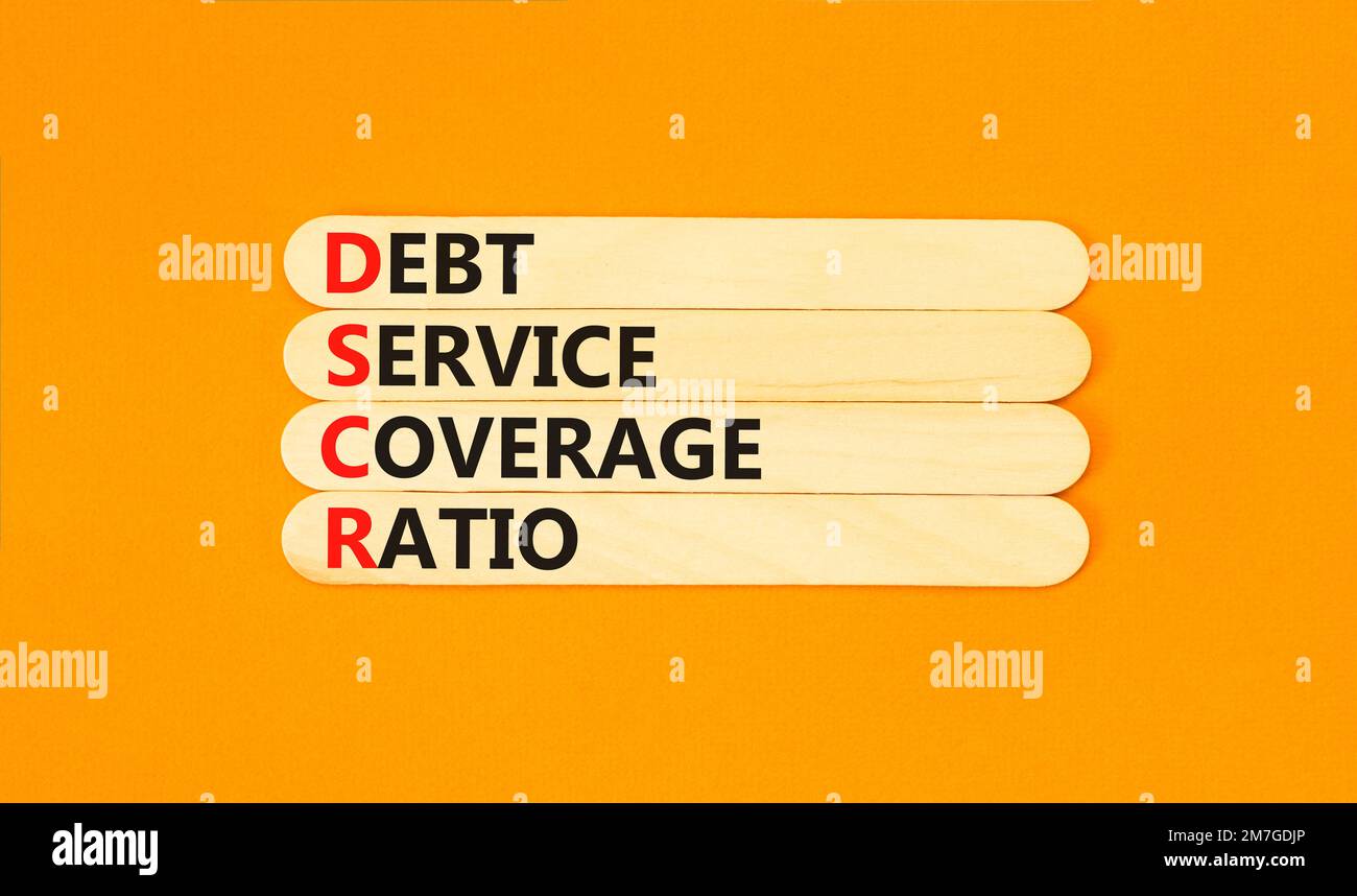 Symbole du ratio de couverture du service de la dette DSCR. Mots de concept  DSCR taux de couverture du service de la dette sur bâton de bois sur beau  fond orange. DSCR