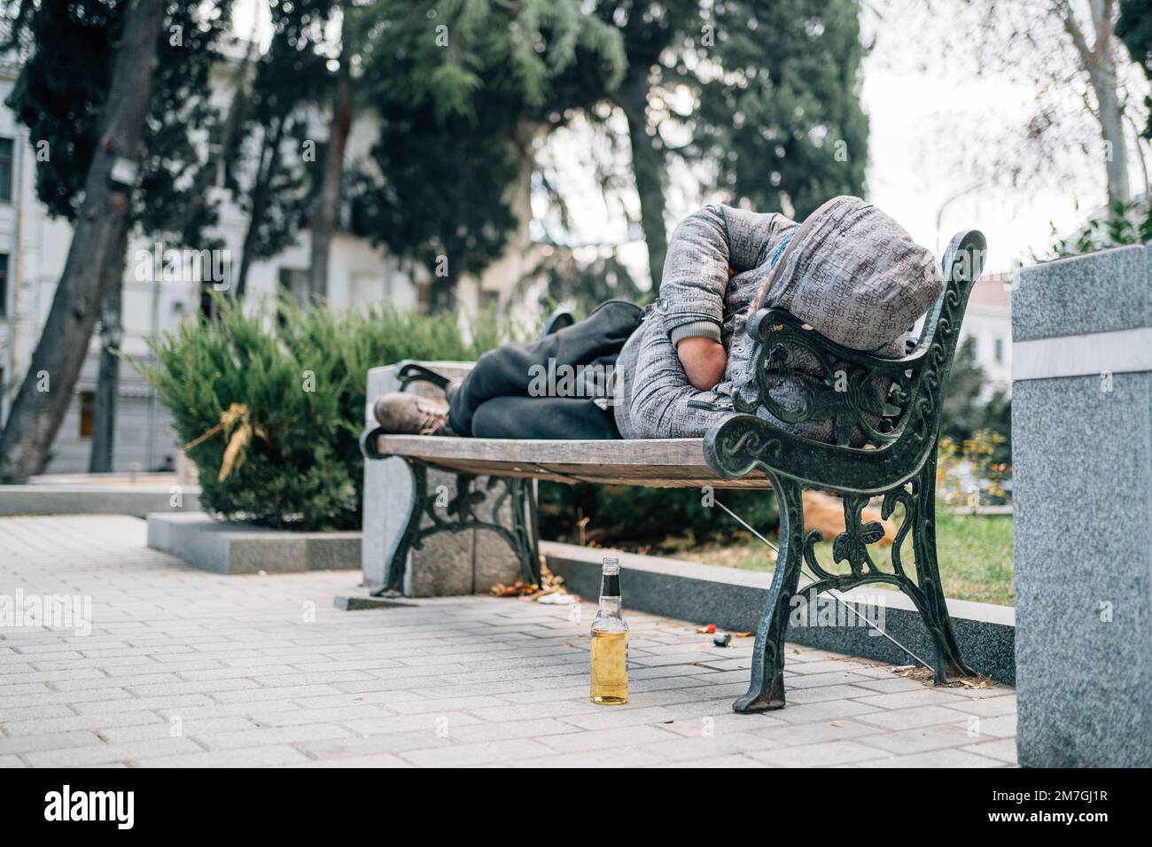Homme sans abri dormant sur banc. Le mendiant dans la rue. Banque D'Images
