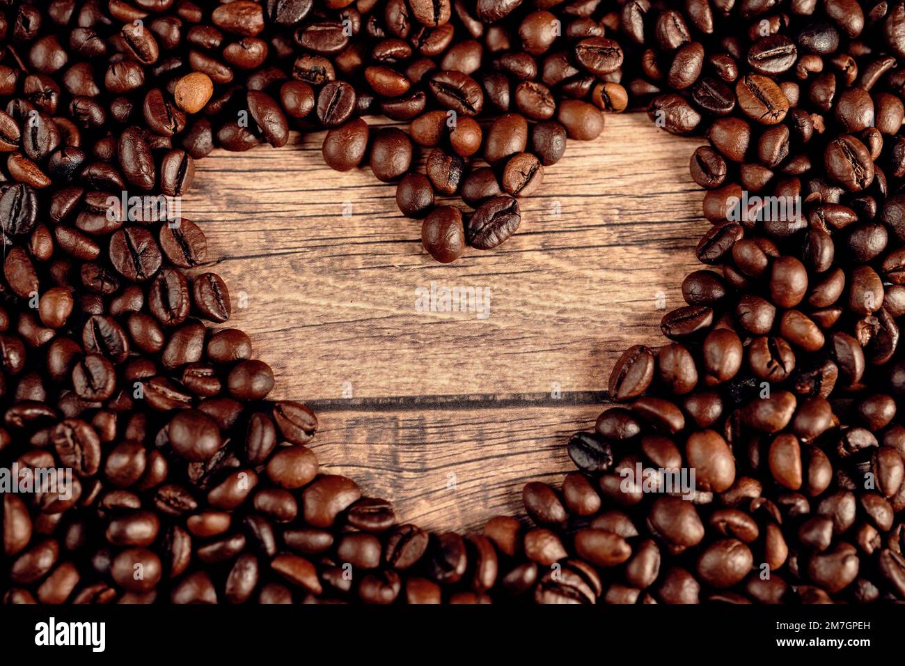 Fond de Saint-Valentin avec coeur de grains de café dans un cadre sombre Banque D'Images