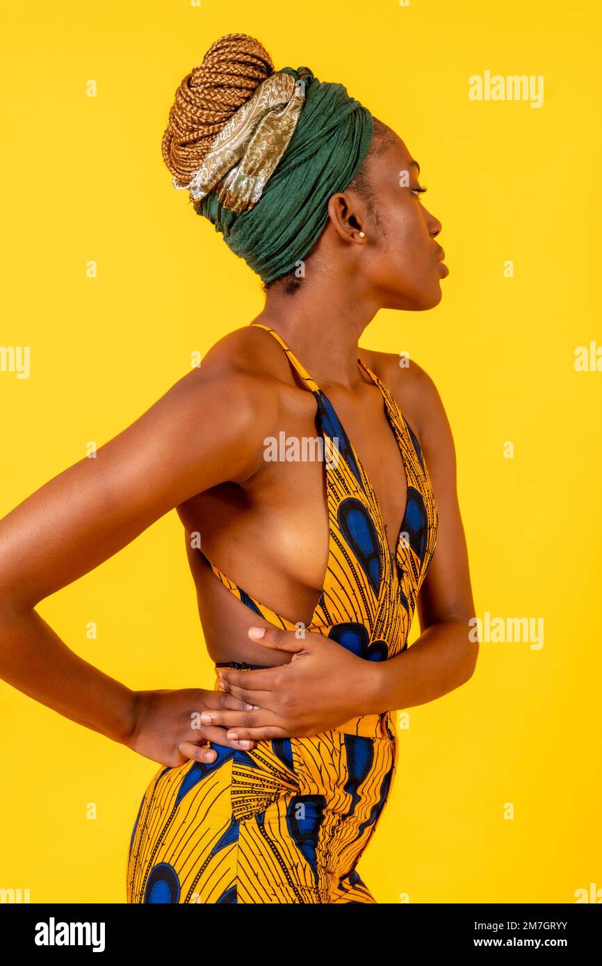 Jeune femme africaine dans le studio sur fond jaune, costume traditionnel, regardant à droite Banque D'Images
