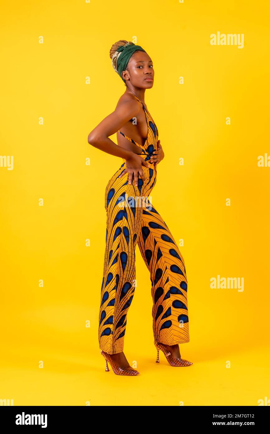 Jeune femme africaine dans le studio sur fond jaune, costume traditionnel Banque D'Images