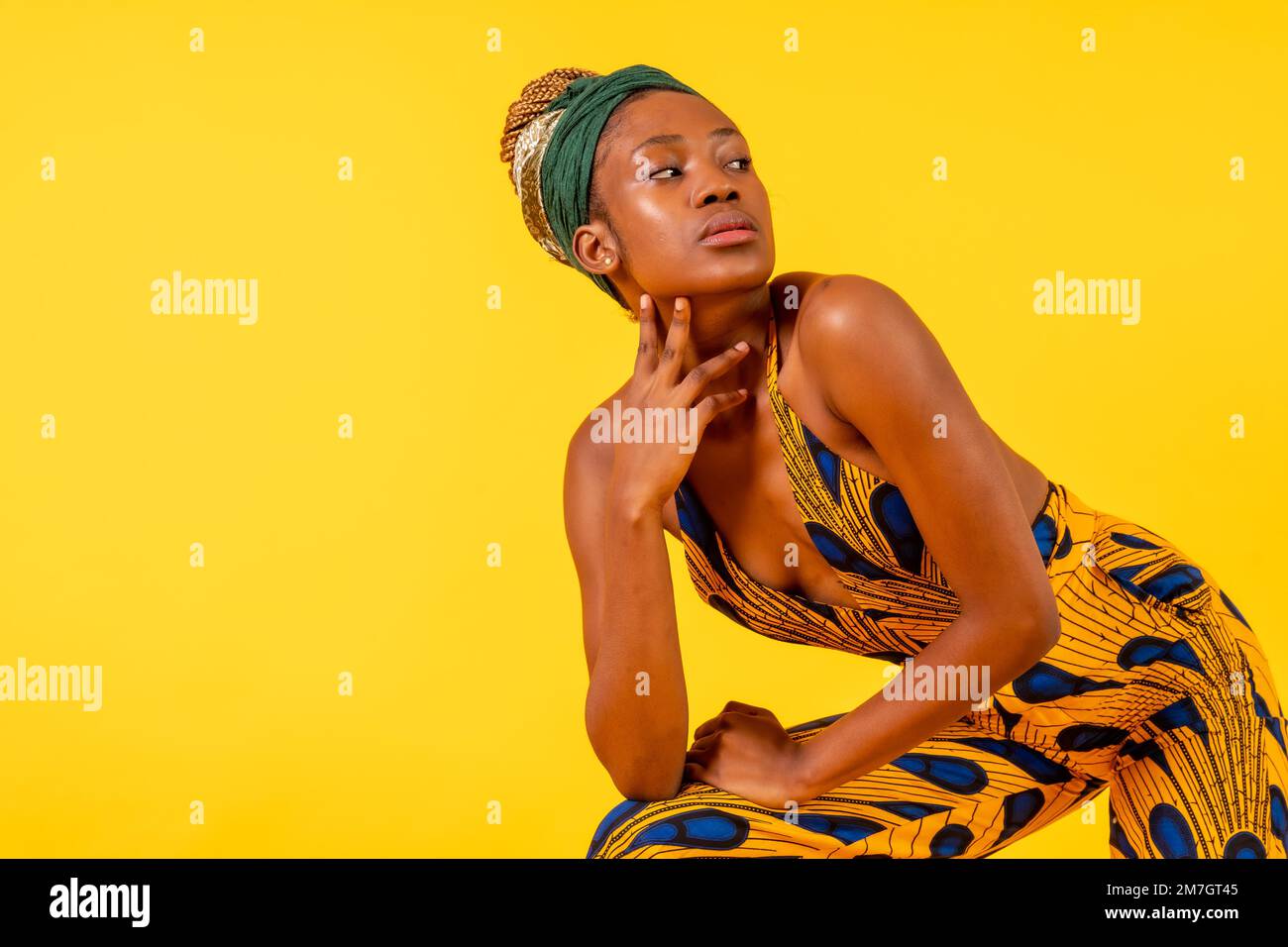 Une femme d'origine noire avec costume traditionnel sur fond jaune, posée à la mode Banque D'Images