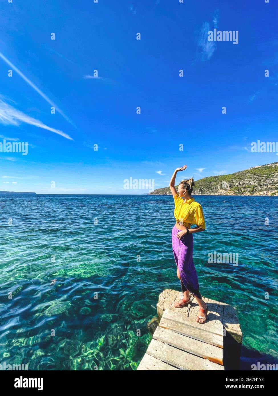Une grande dame heureuse sourit au soleil sur le fond de la mer et du paysage de l'île. Banque D'Images