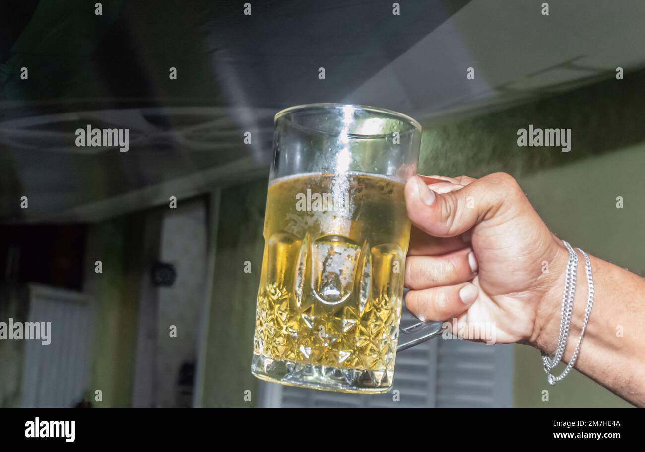 Tasse à bière avec bière à l'intérieur et tenue à la main, espace de copie à gauche. Banque D'Images