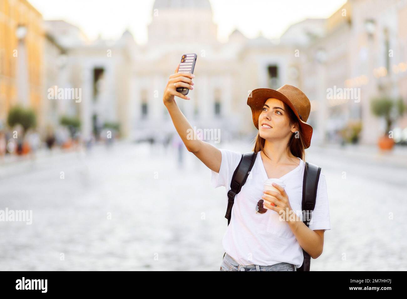 Portrait bonne jeune femme prenant photo de selfie et regardant l'appareil photo pendant que dans le centre ville sur la place. Femme voyageur blogueur Banque D'Images