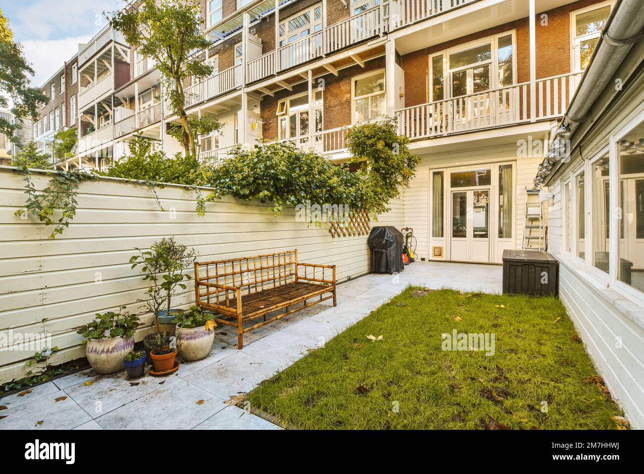 une petite cour avec un banc et un jardinière en pot sur le sol en face d'un immeuble d'appartements Banque D'Images