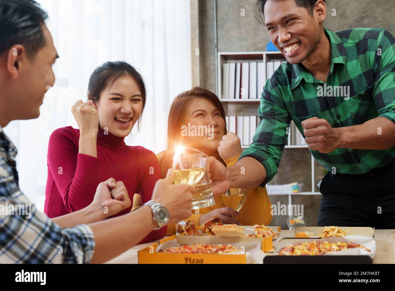 Les amis à la fête d'anniversaire se trinquent avec des verres de champagne et de pizza, en appréciant les vacances de Noël, pizza sur la table. Fête des fêtes. Banque D'Images