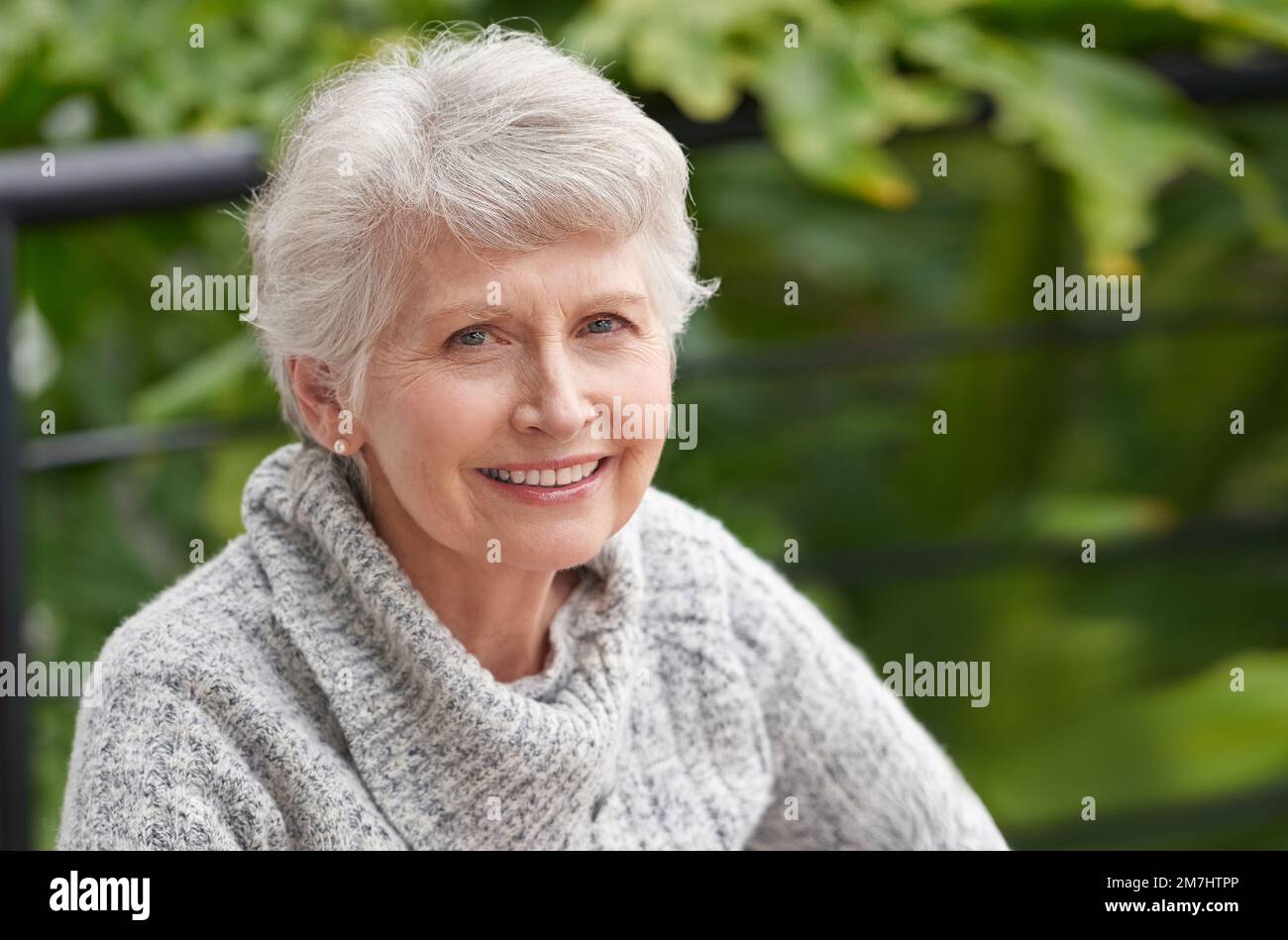 Juste vivre la vie un jour à la fois. Portrait d'une femme âgée assise à l'extérieur. Banque D'Images