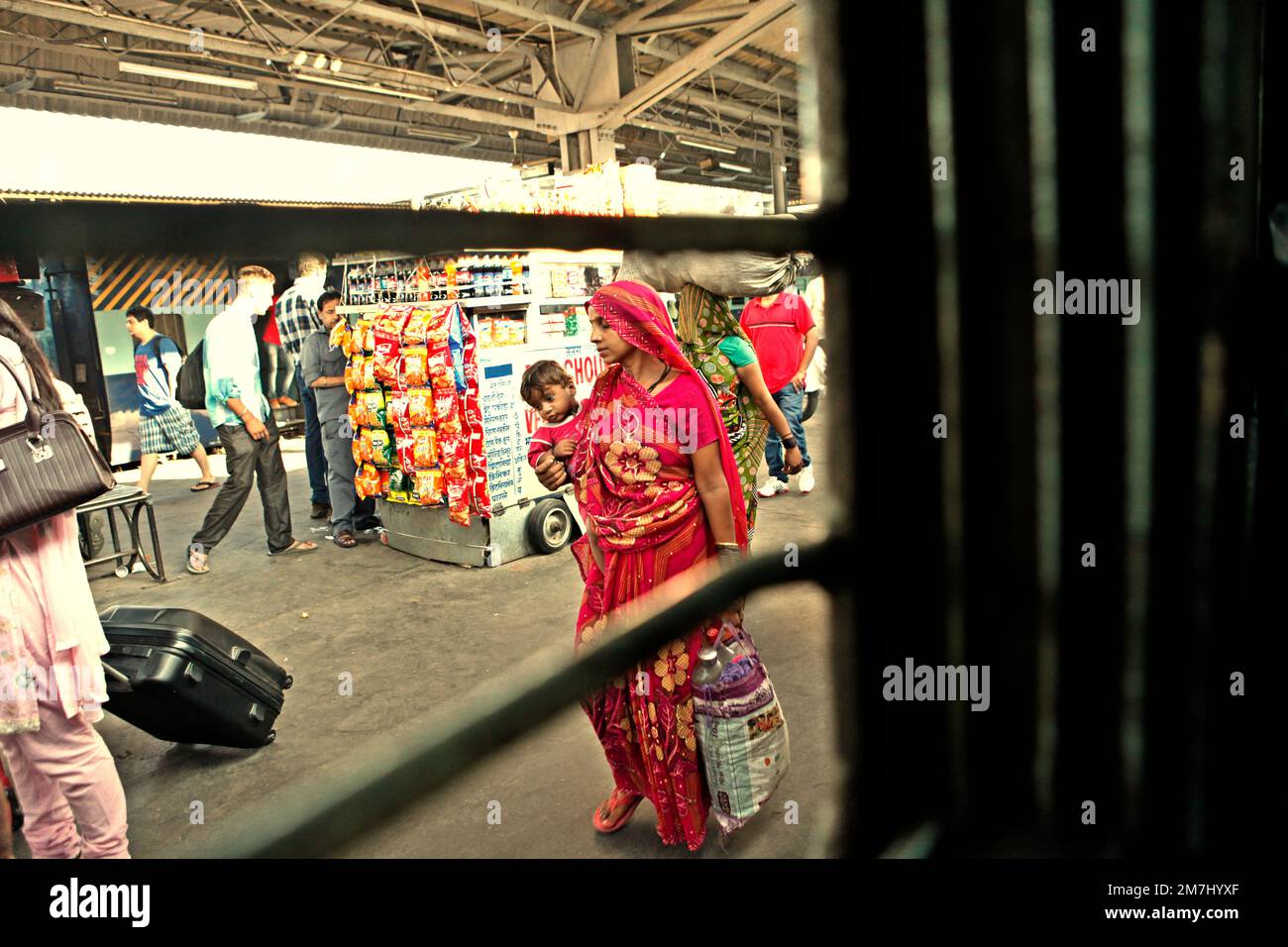 Une femme tenant un bébé alors qu'elle marche sur la plate-forme passager à la gare de New Delhi, en Inde. Banque D'Images