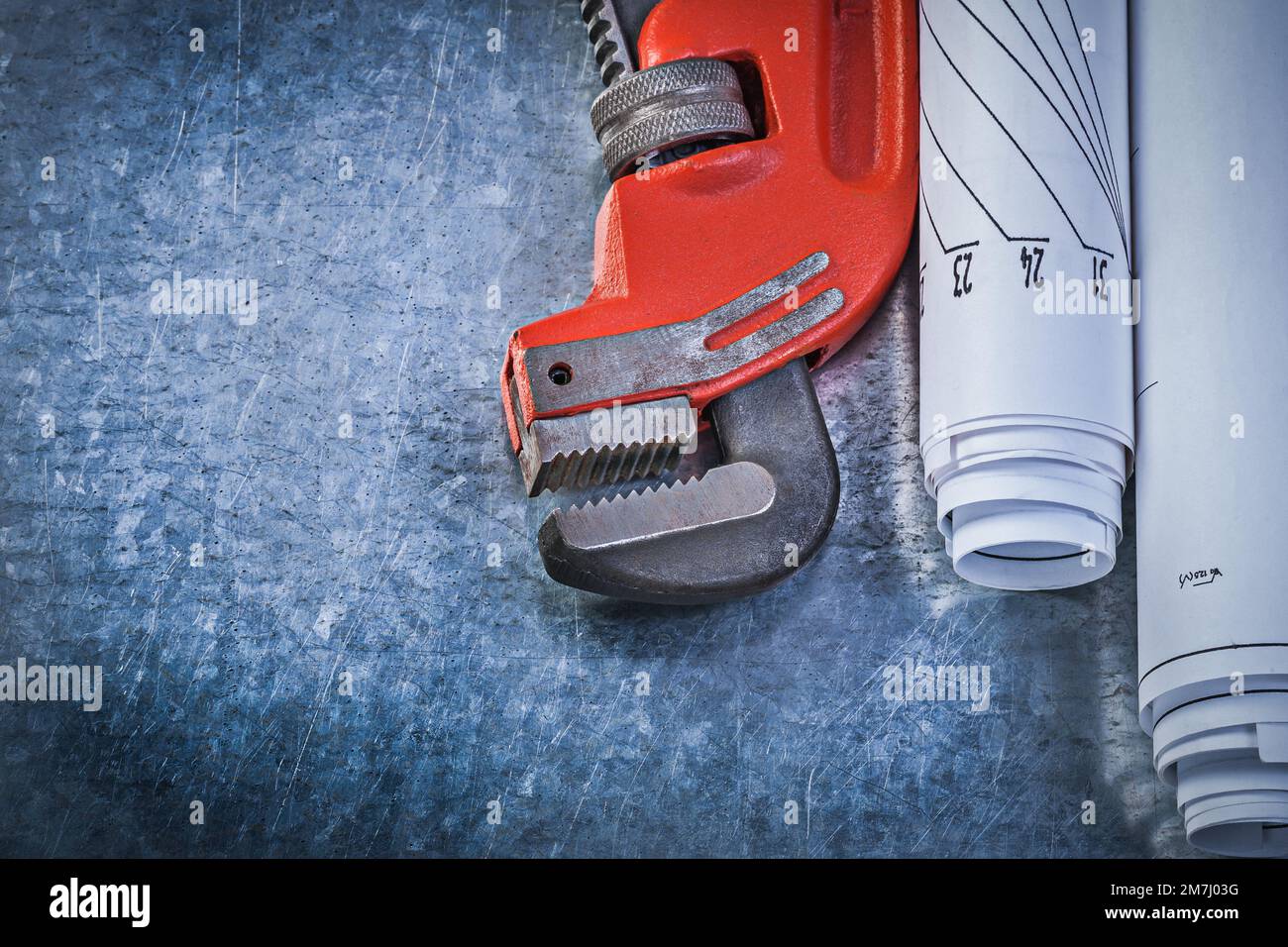 La clé de singe a enroulé les dessins de construction sur le concept de plomberie de fond métallique rayé. Banque D'Images